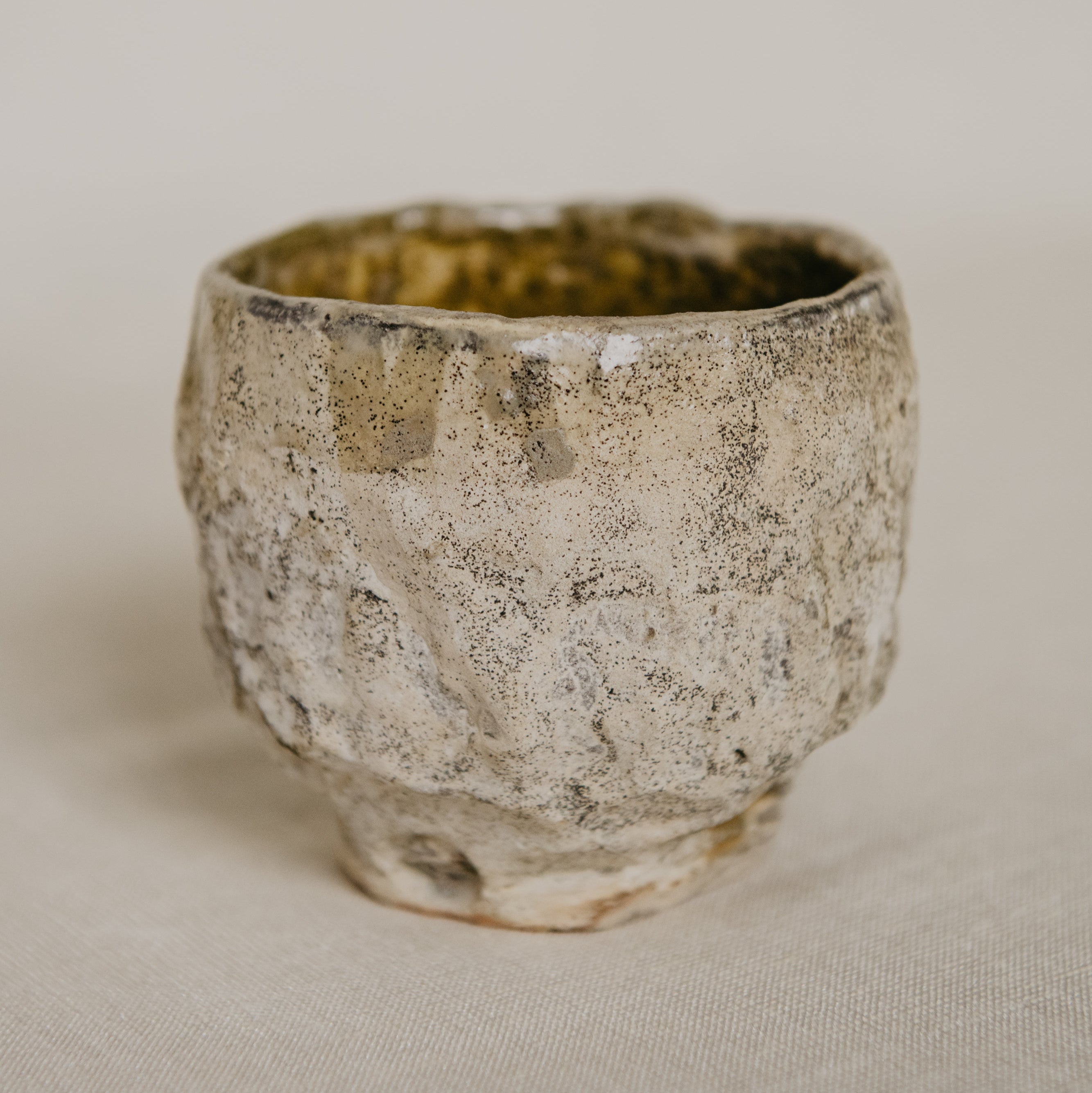 Vintage ceramic cup with textured surface on a beige background
