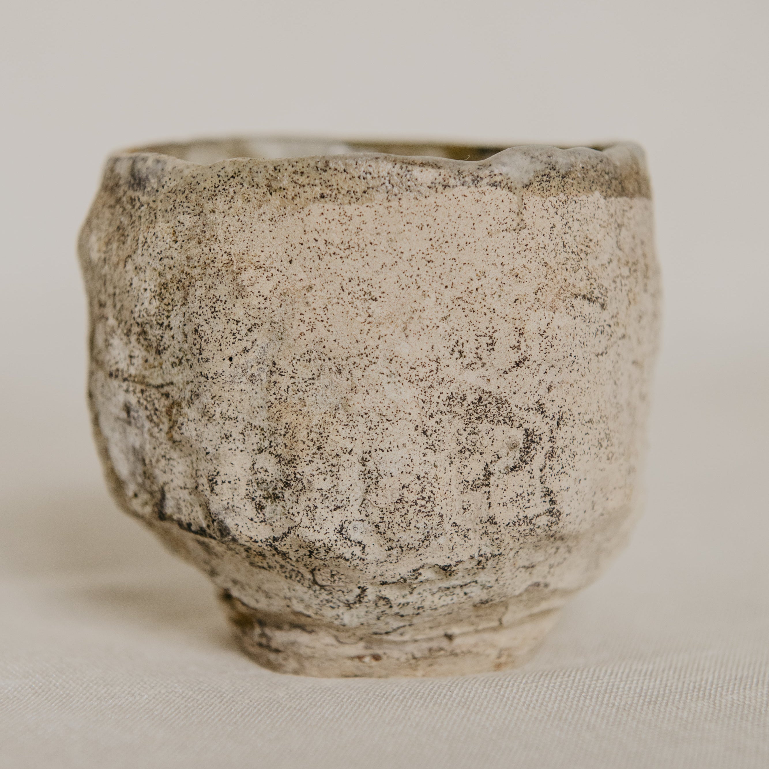 Small ceramic cup with textured surface on a neutral background