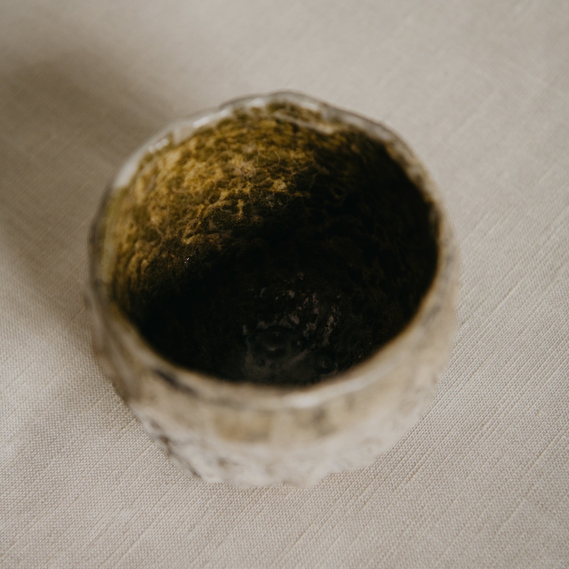 Mossy stone container on a textured beige surface