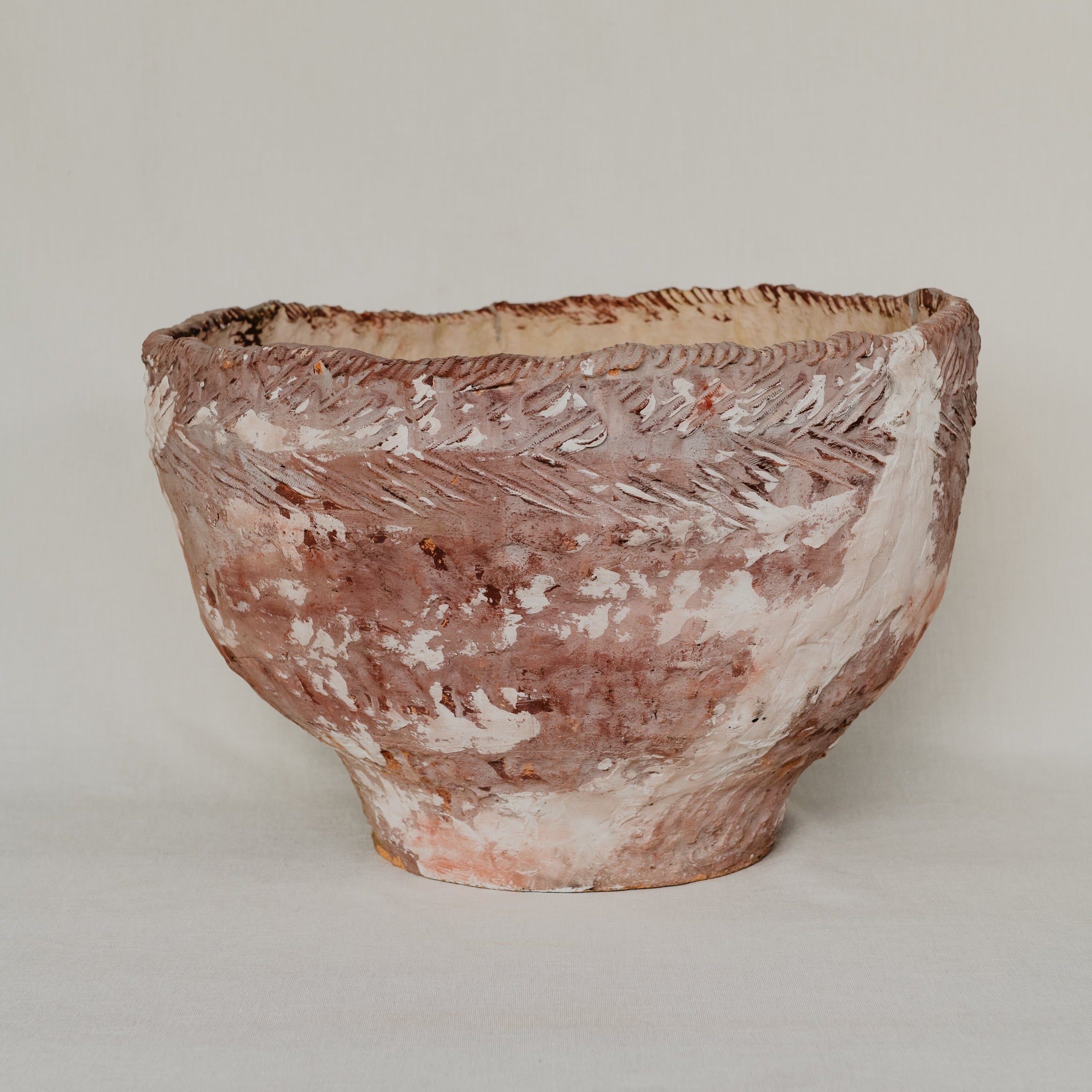 Terracotta bowl with textured surface on a plain background