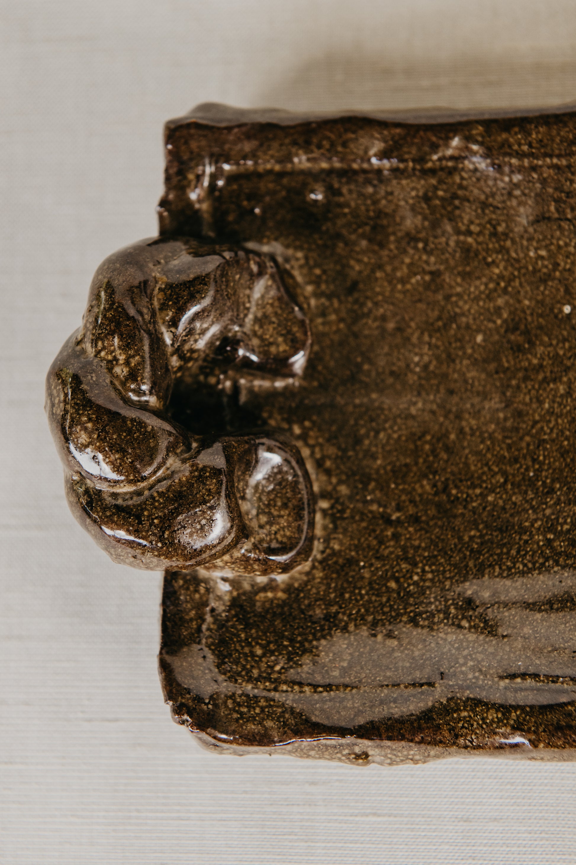 Close-up of a textured brown ceramic object with a white background