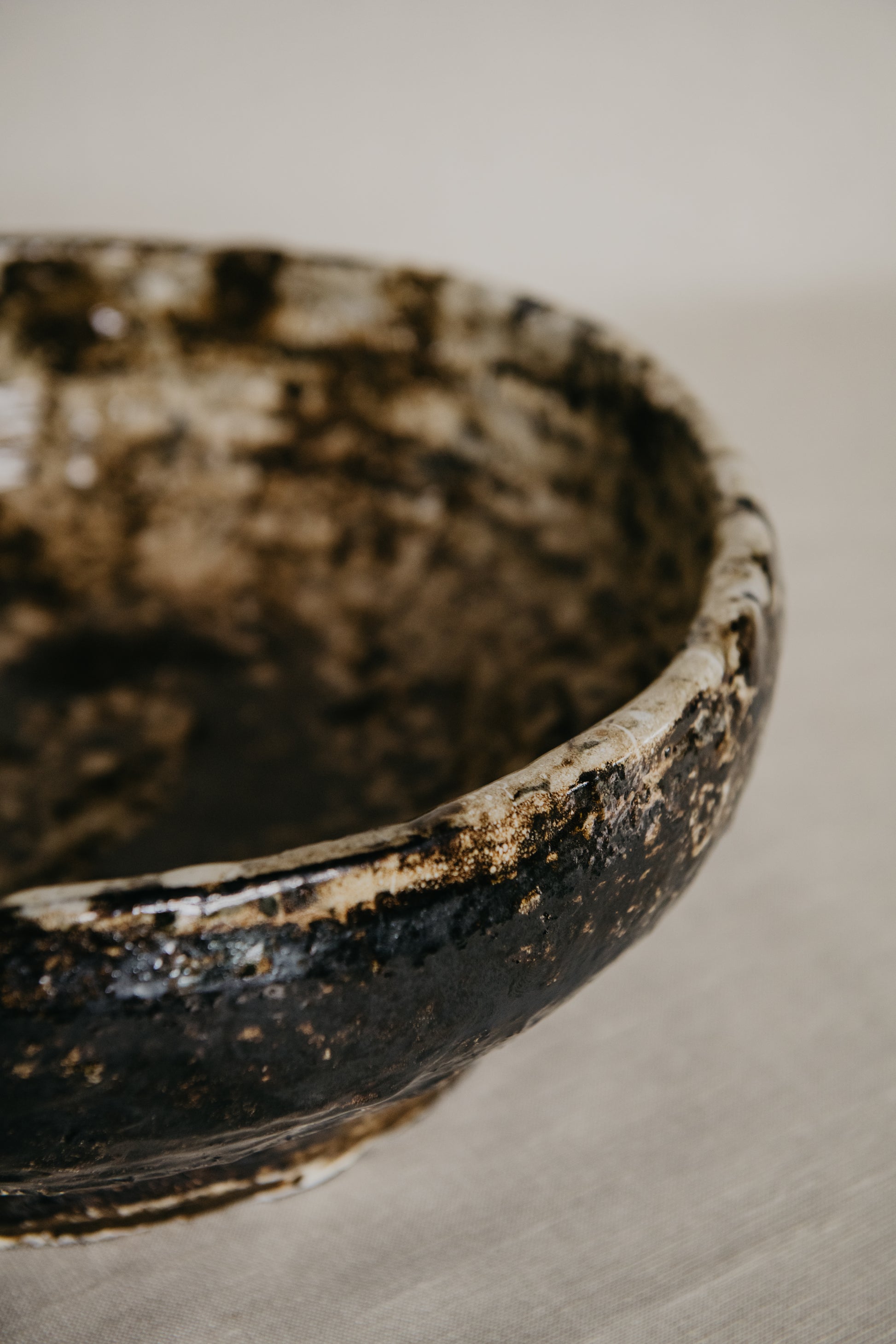 Close-up of a rustic ceramic bowl with a textured surface on a neutral background