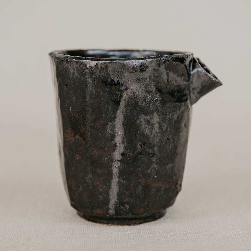 Black ceramic pitcher on a light gray background