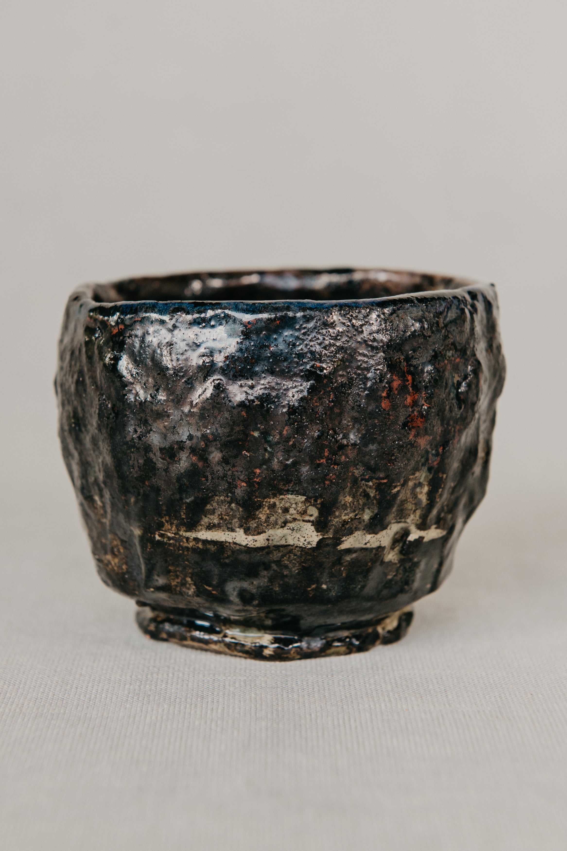 Black ceramic cup with textured surface on a light gray background