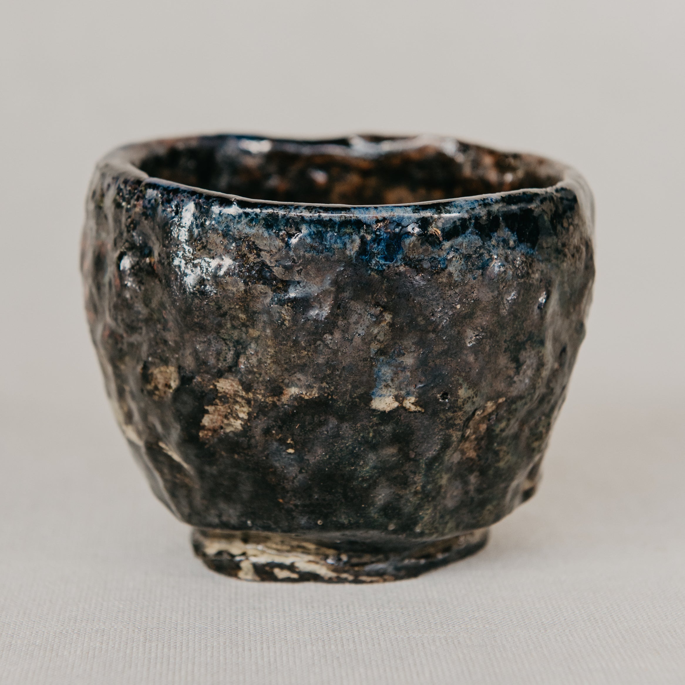 Black ceramic cup with textured surface on a light gray background