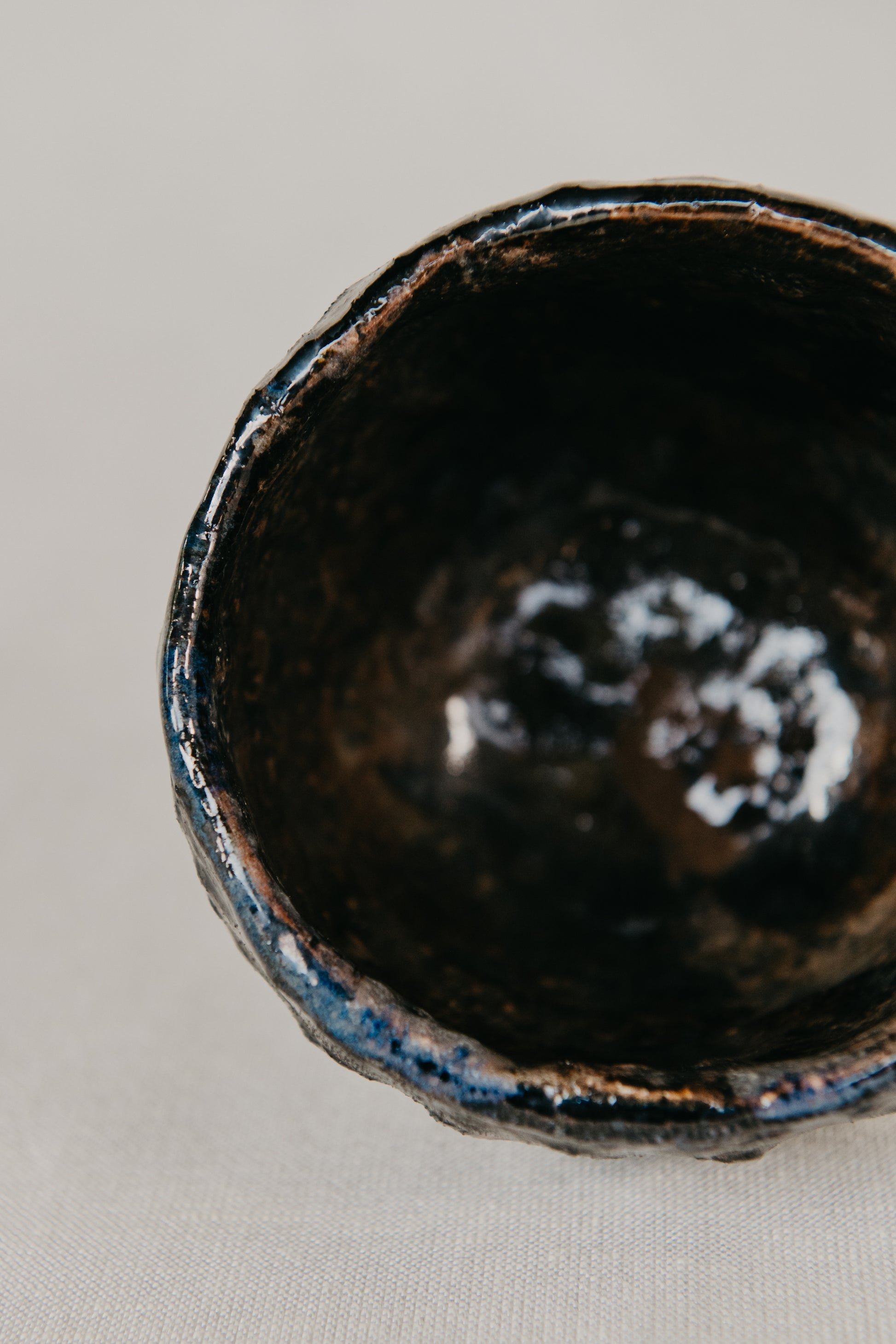 Close-up of a dark ceramic bowl with a textured surface on a light gray background