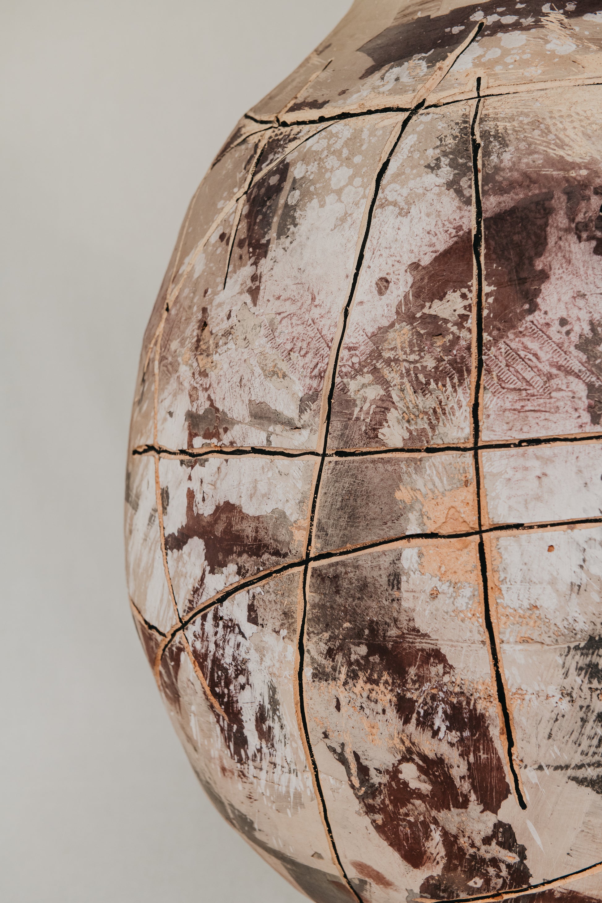 Close-up of a cracked and weathered sphere with a neutral background