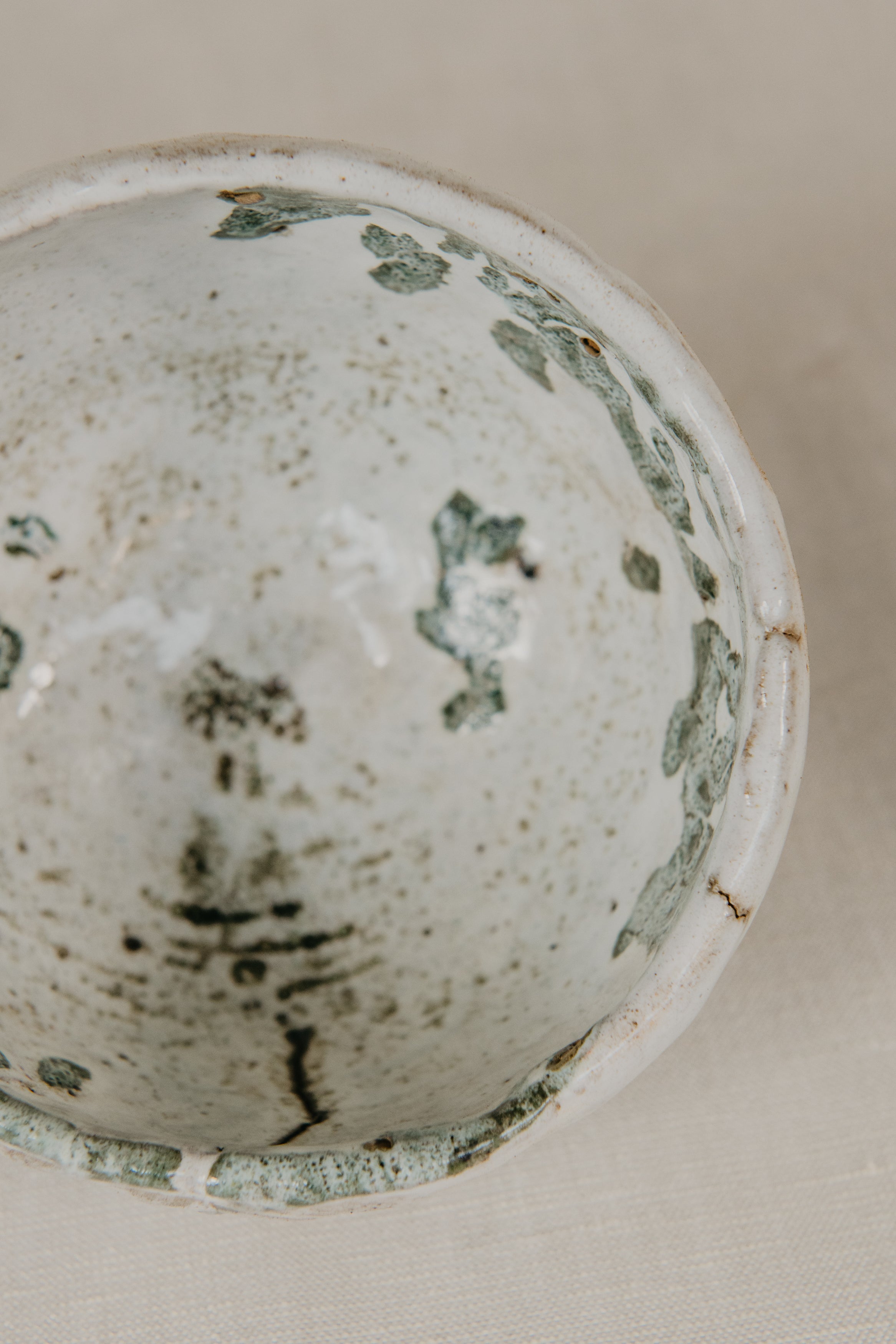 Close-up of a ceramic bowl with speckled glaze on a neutral background