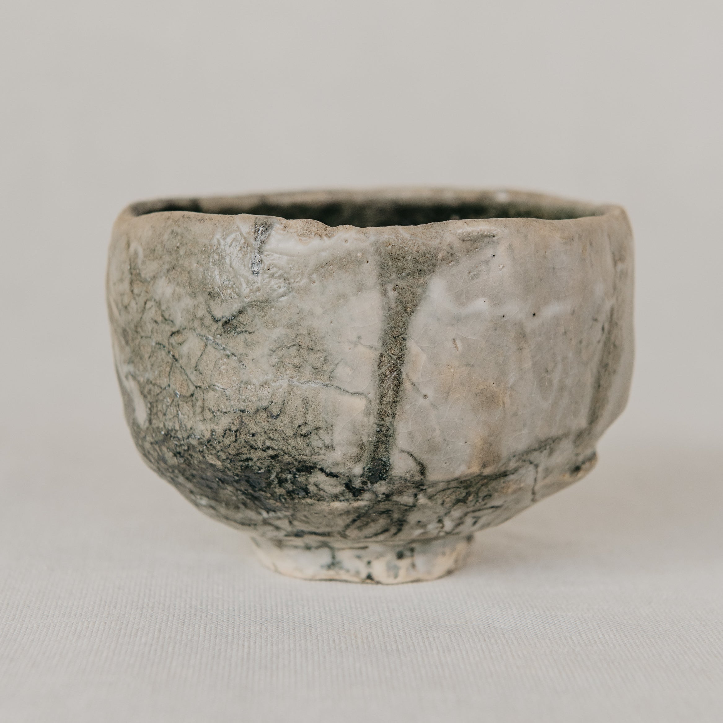 Small ceramic cup with textured surface on a plain background