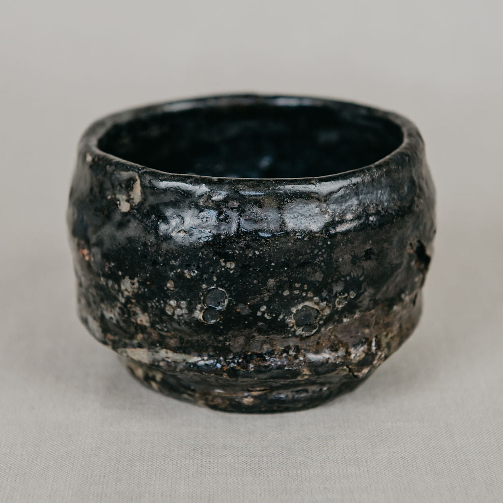 Black ceramic cup with textured surface on a gray background
