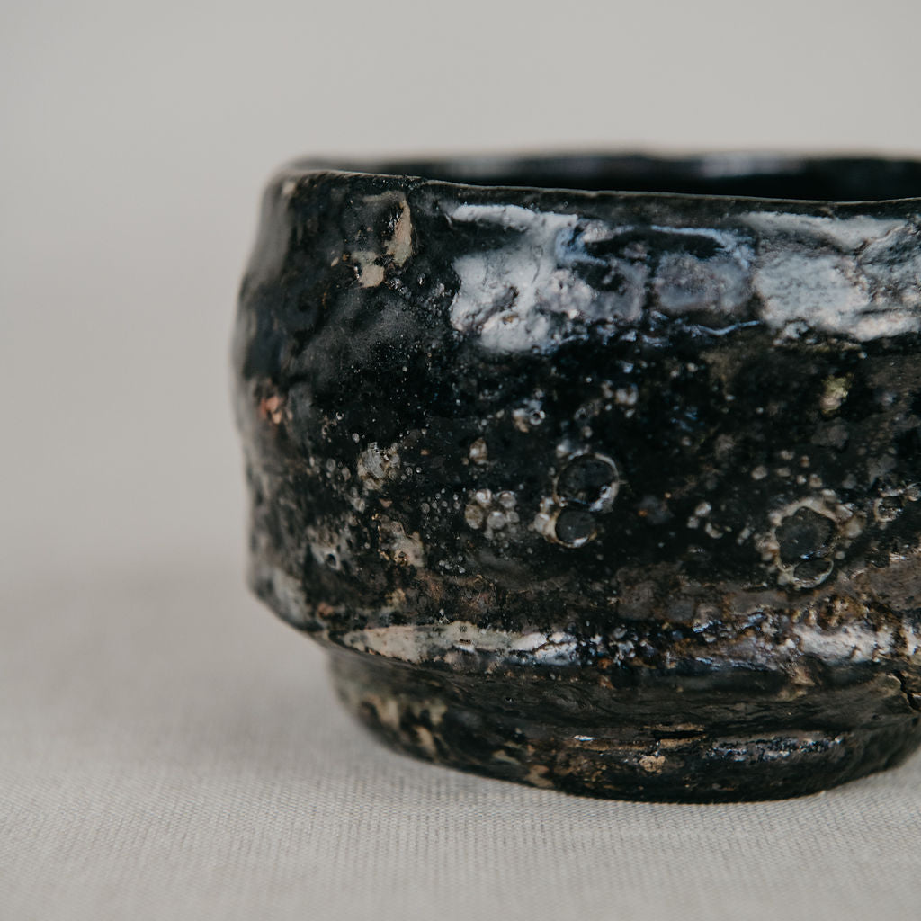 Close-up of a black ceramic bowl with a textured surface on a light gray background