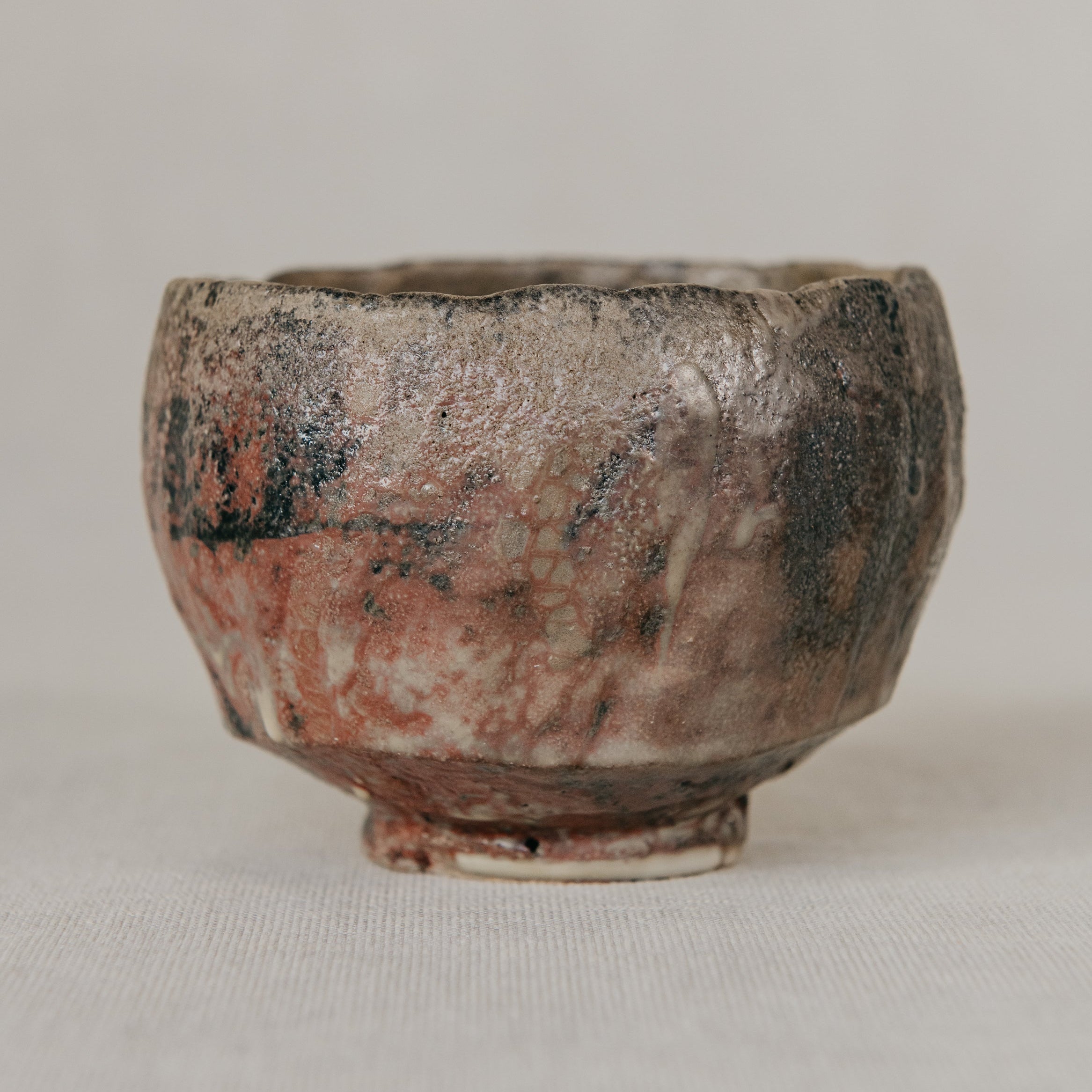 Small ceramic cup with a textured surface on a plain background