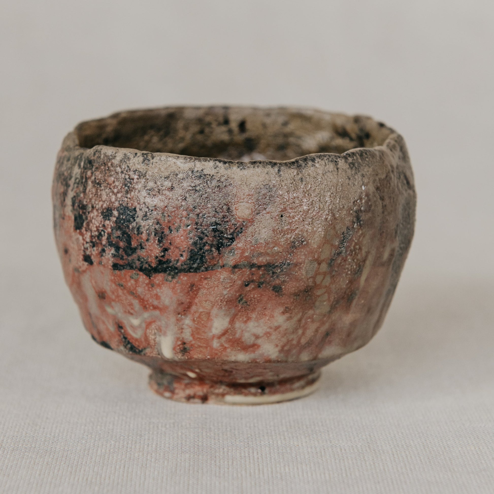 Small ceramic cup with a textured surface on a light gray background