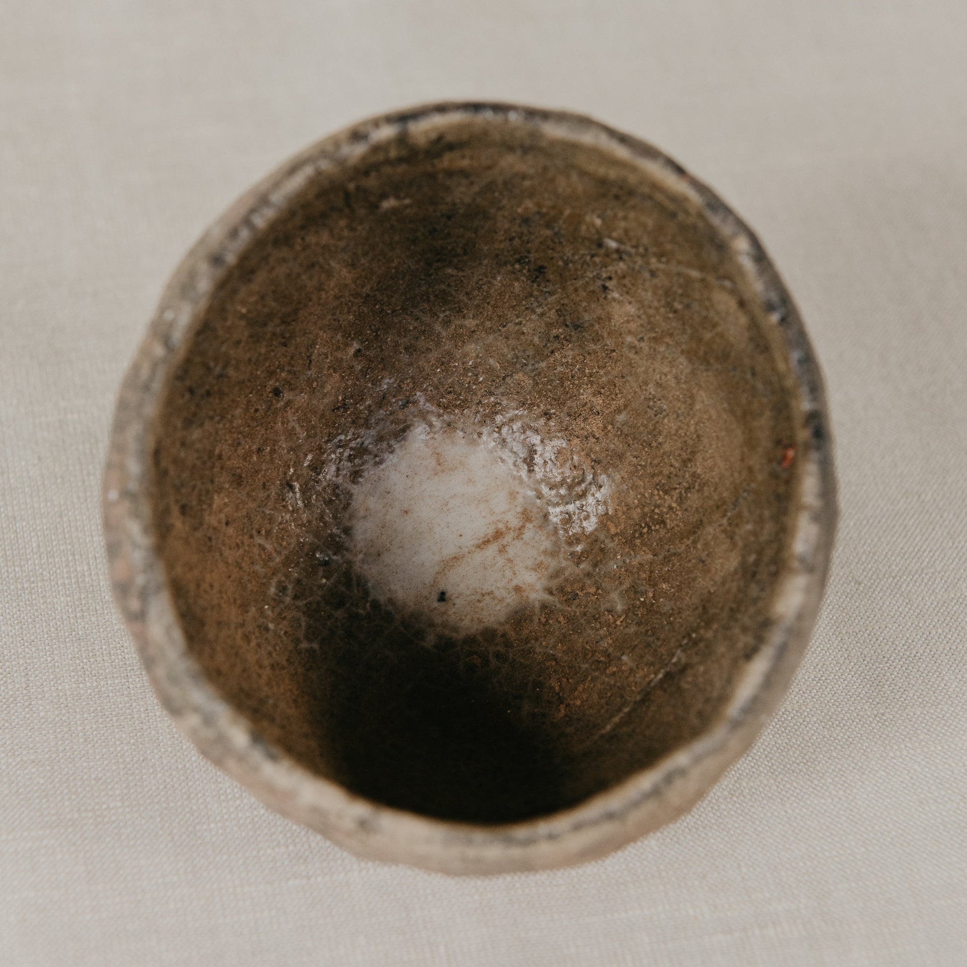 Brown ceramic cup with a white interior on a light gray background