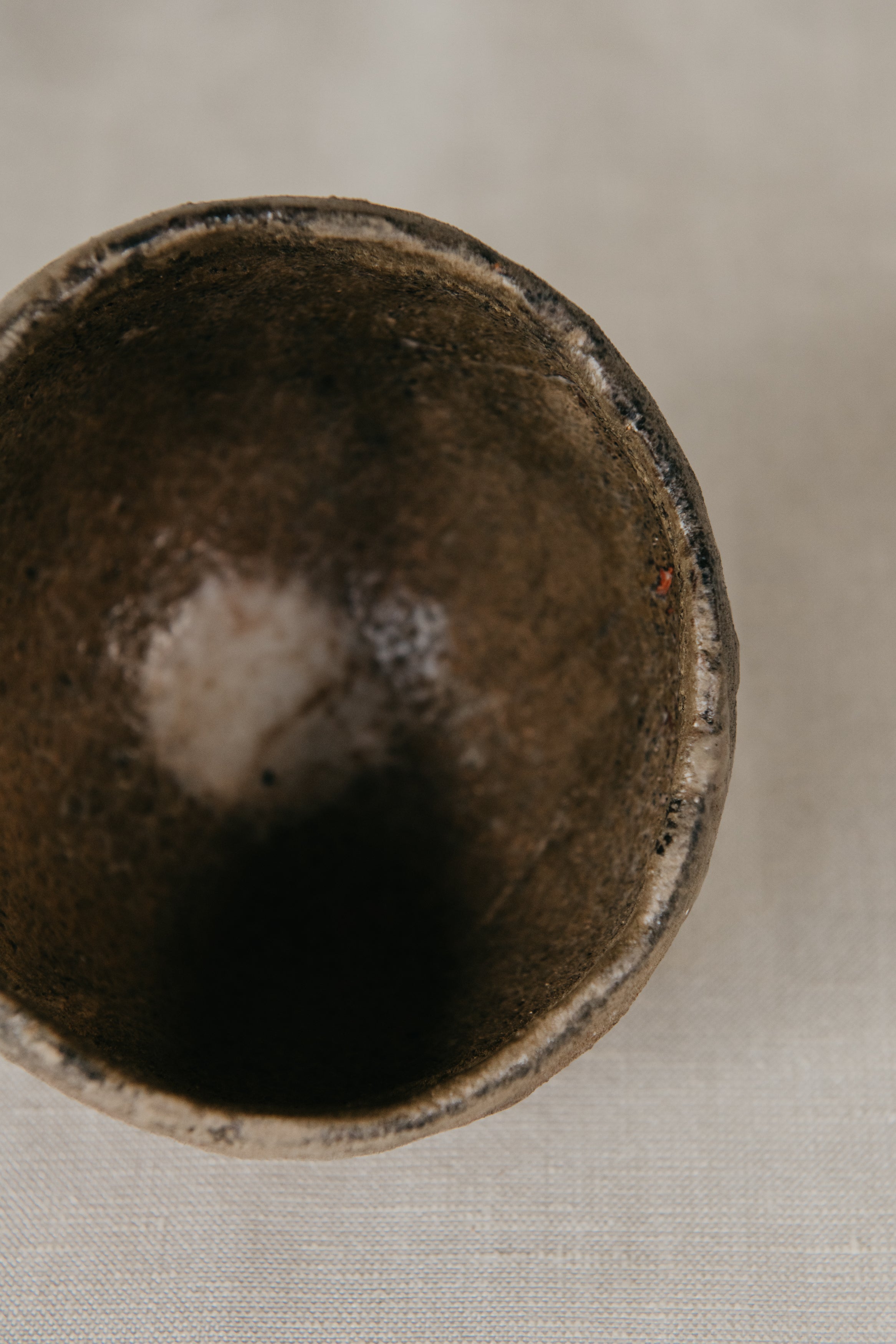 Close-up of a dark brown ceramic cup on a light fabric background