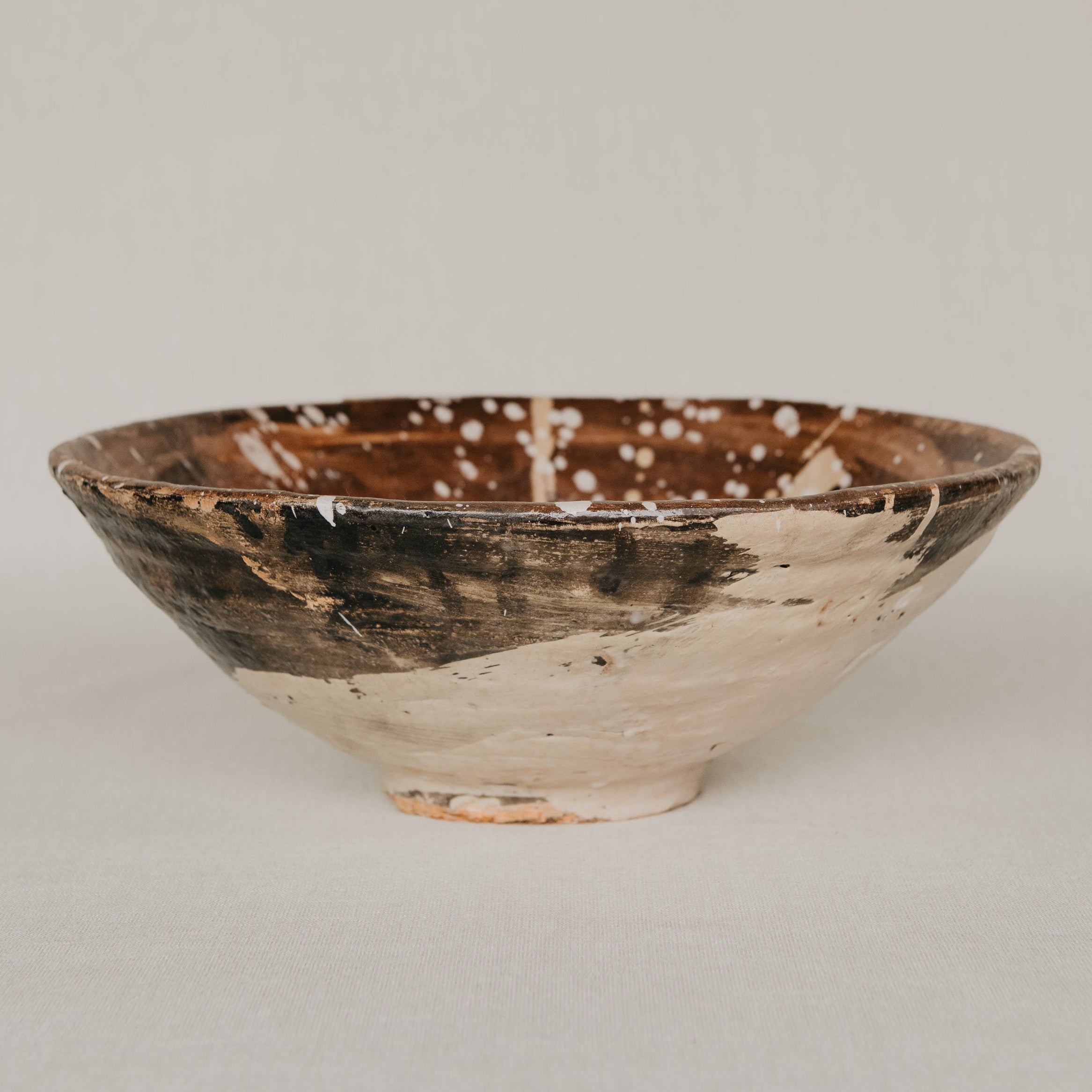 Ceramic bowl with brown and white speckled design on a light gray background