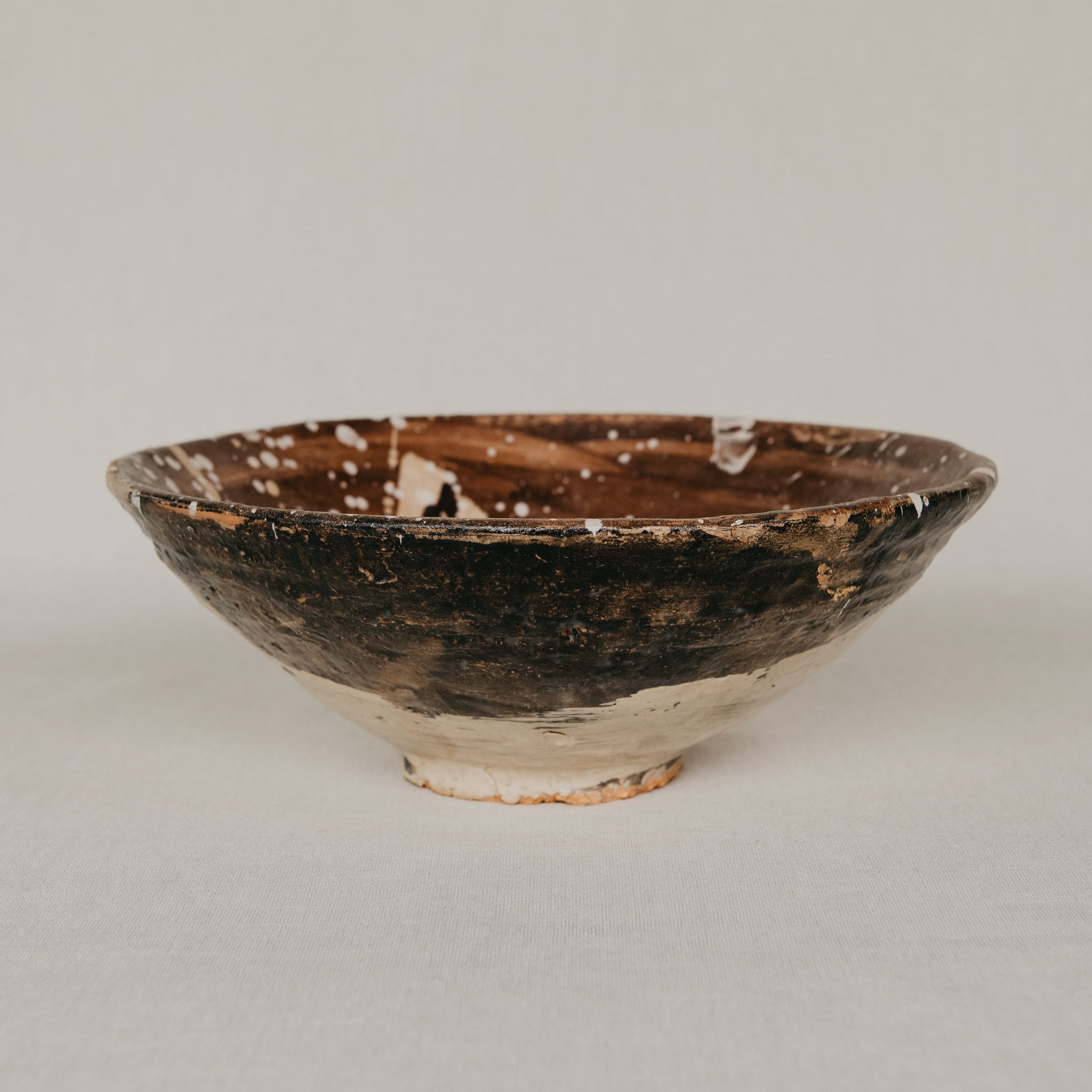 Vintage ceramic bowl with brown glaze on a plain background