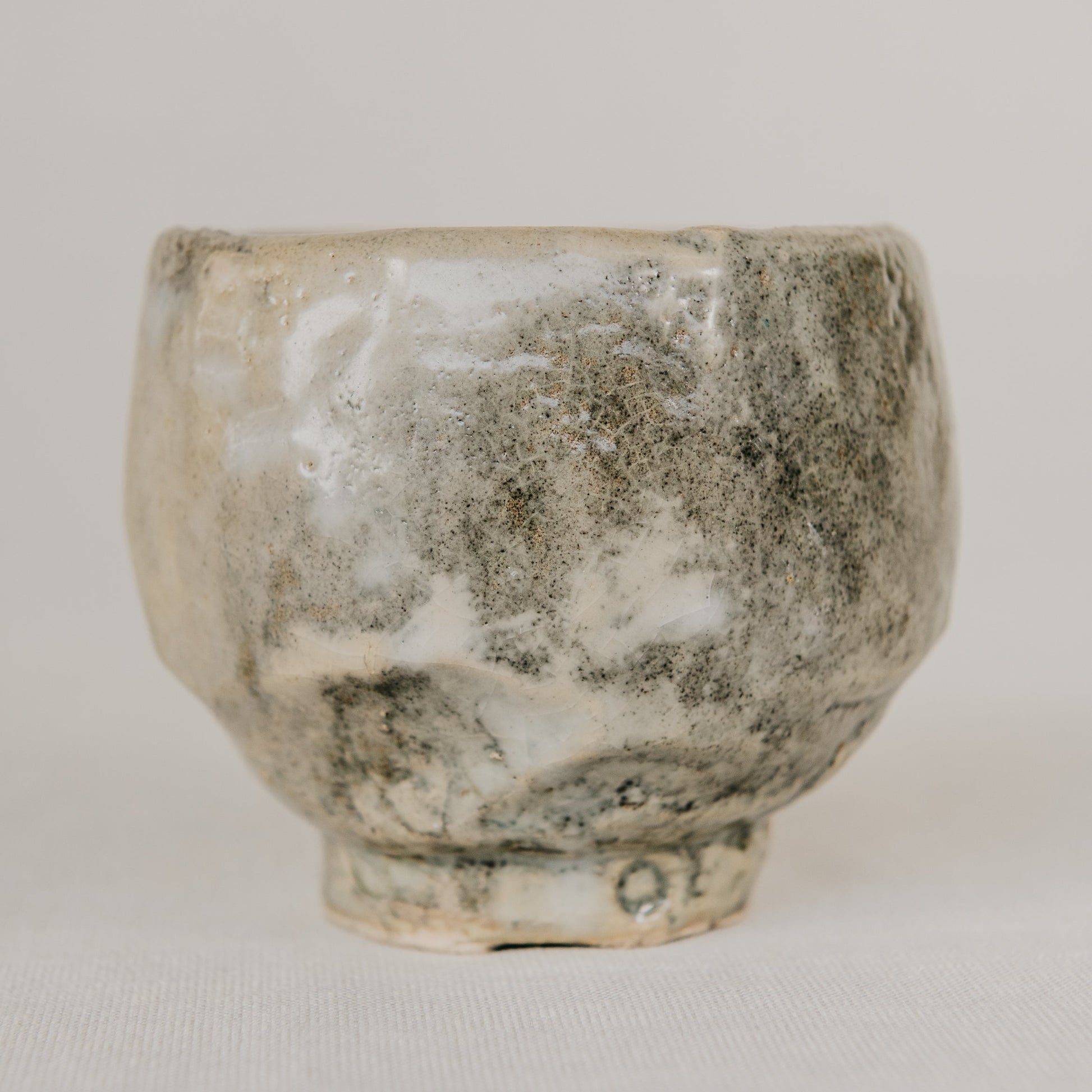 Small ceramic cup with a textured surface on a plain background