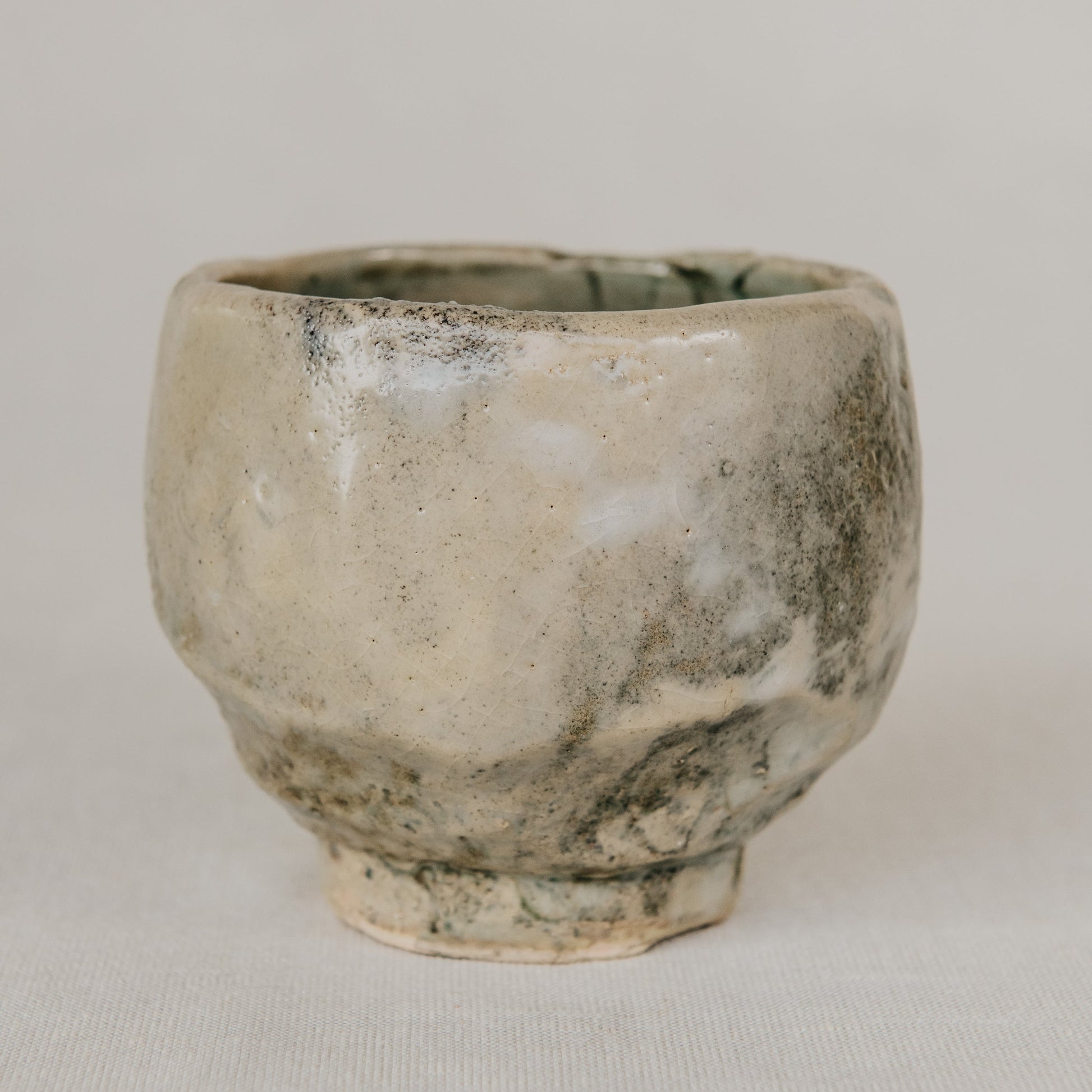 Small ceramic cup with a textured surface on a plain background