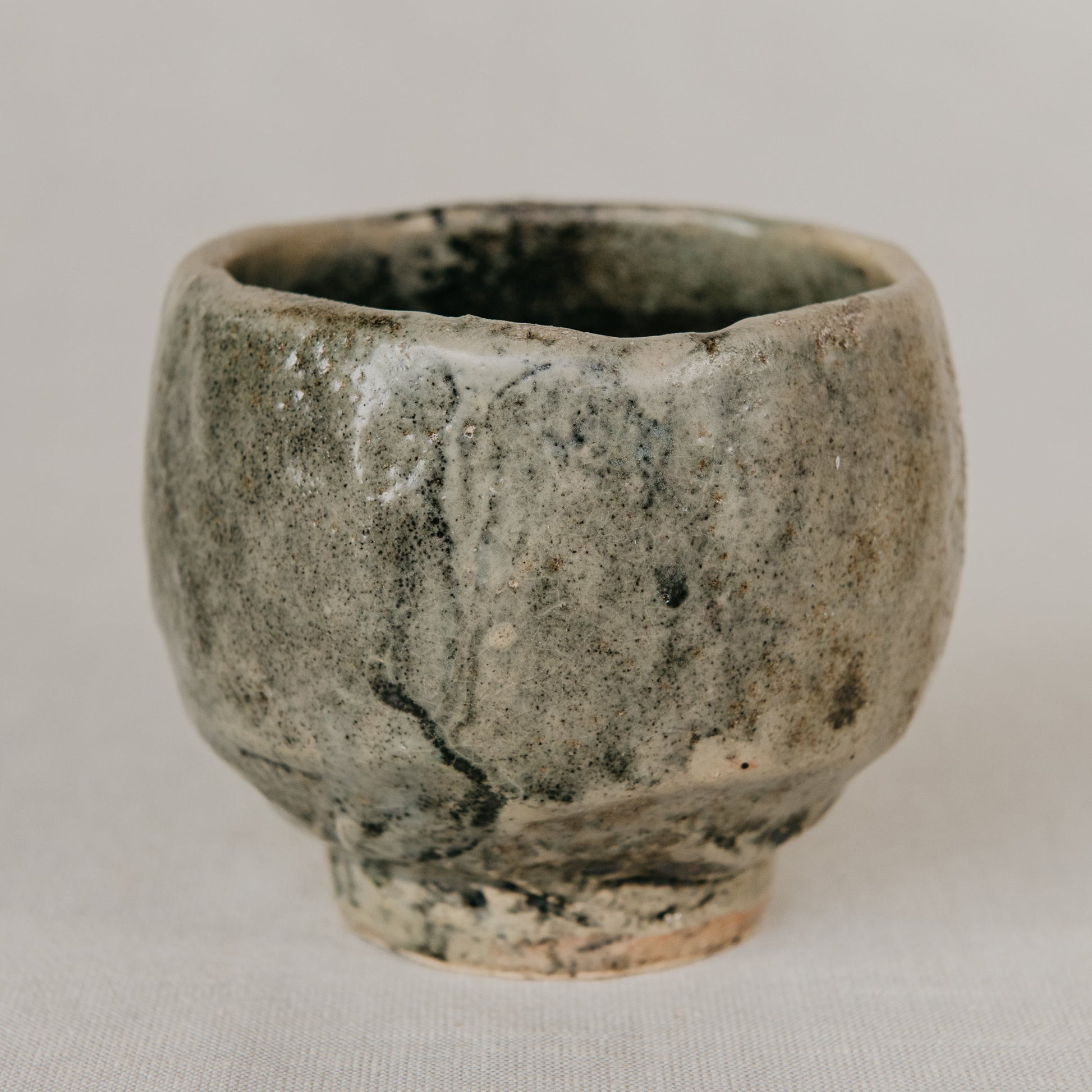 Small ceramic cup with a textured surface on a plain background