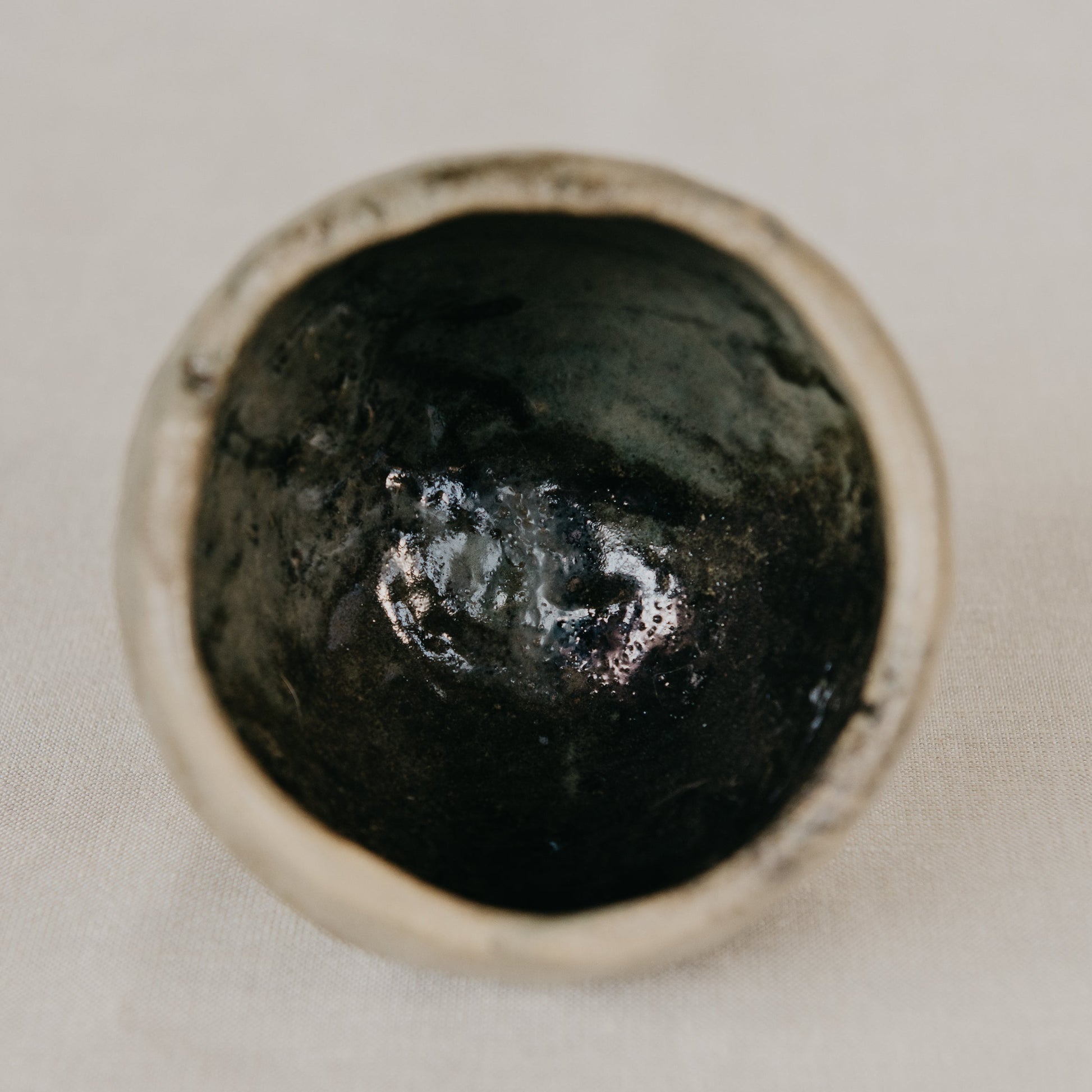 Close-up of a dark stone in a silver frame on a light background
