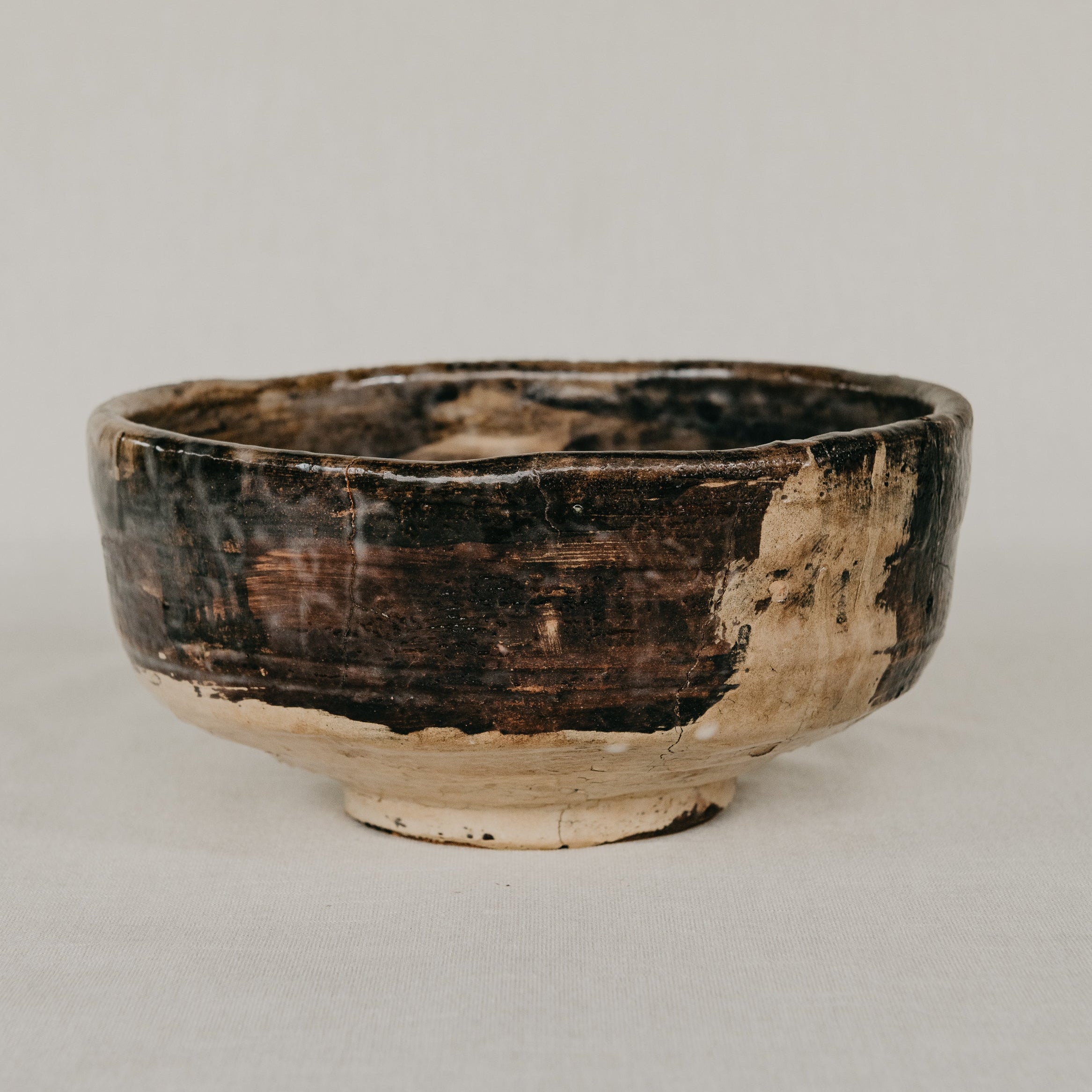 Ceramic bowl with a dark brown glaze on a light gray background