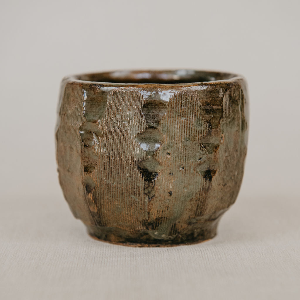 Textured ceramic cup on a beige background