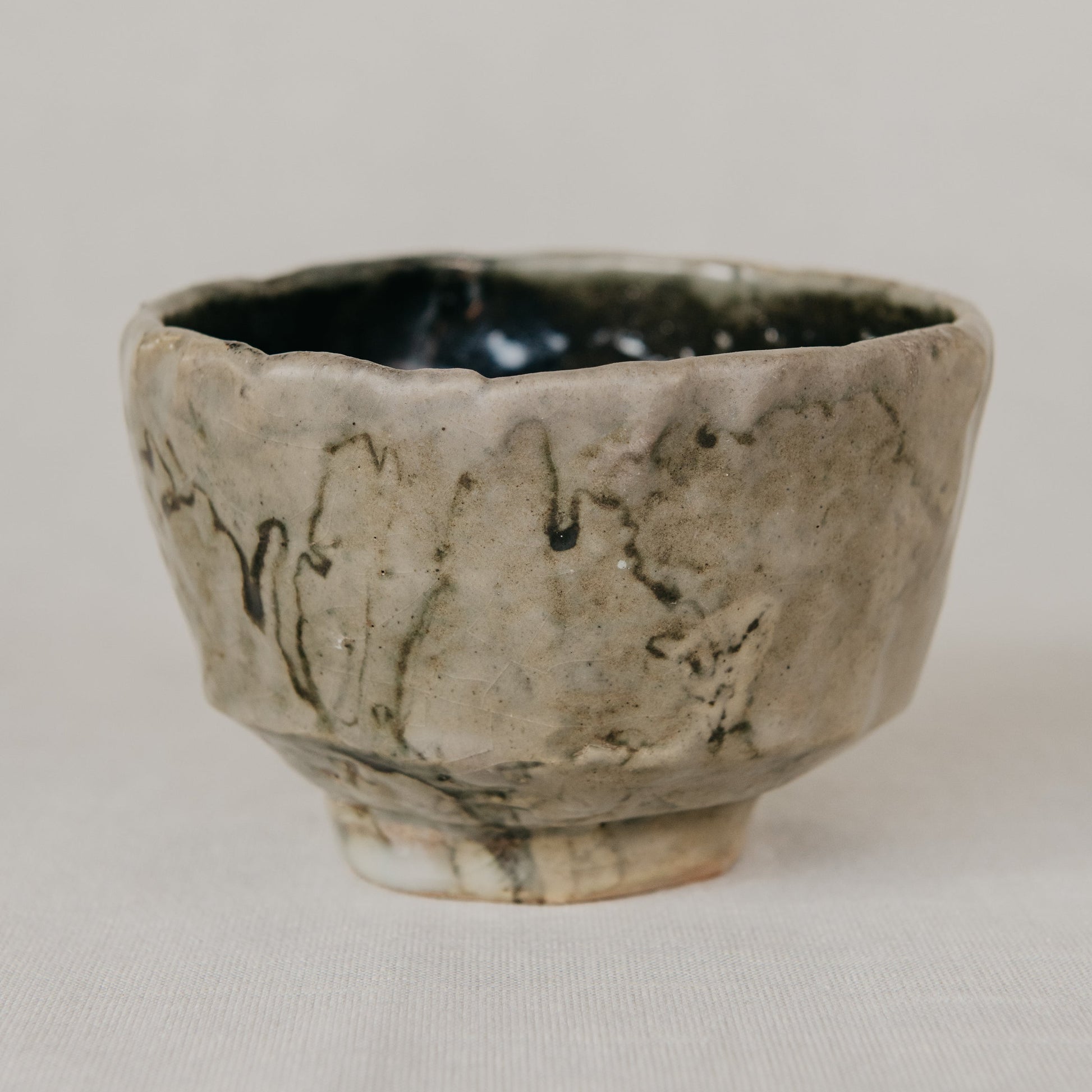 Handcrafted ceramic cup with textured surface on a neutral background
