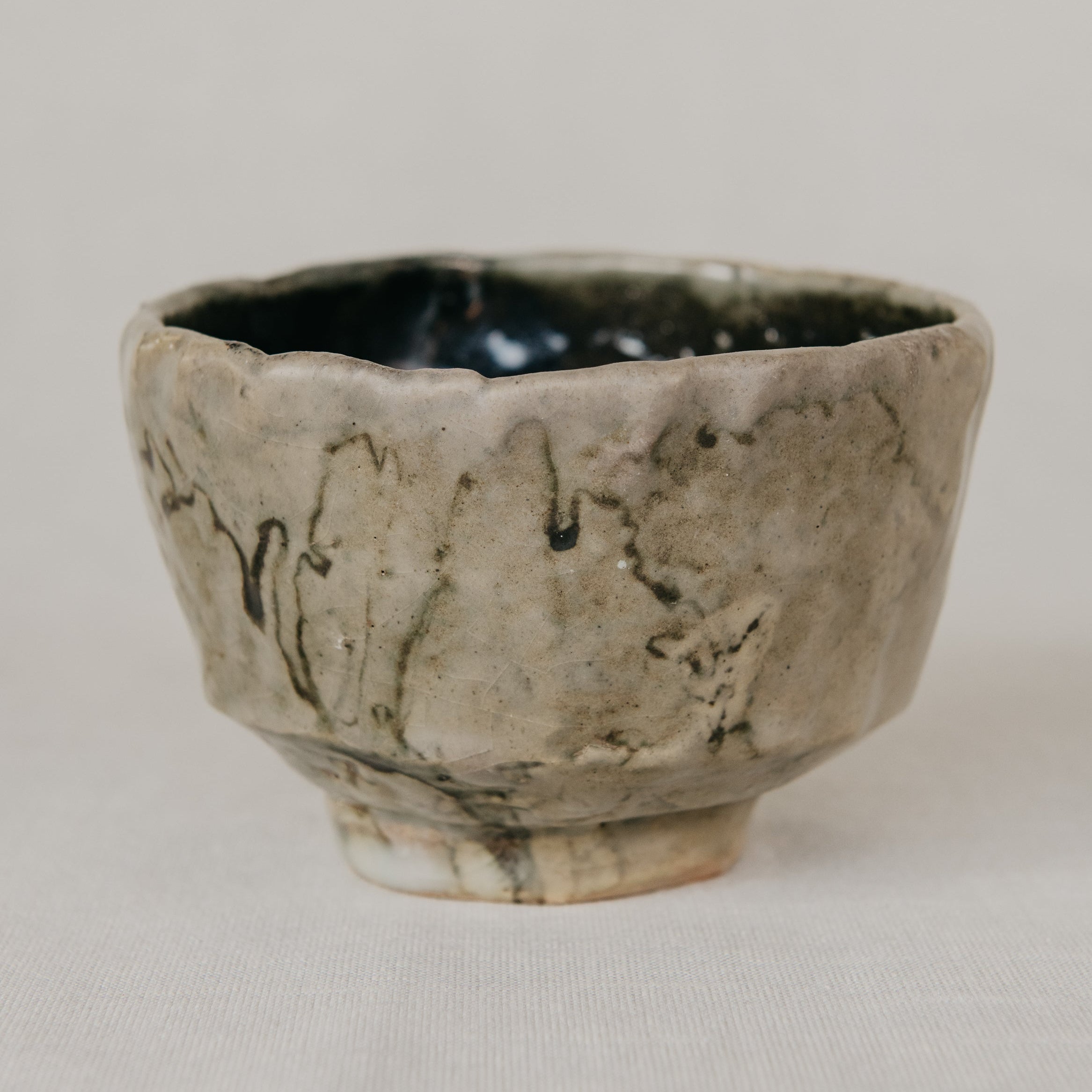 Handcrafted ceramic cup with textured surface on a neutral background