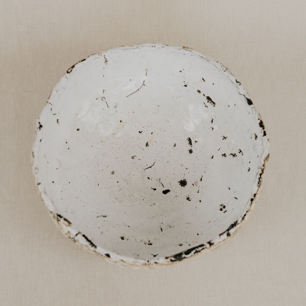 Round ceramic dish with speckled texture on a beige background