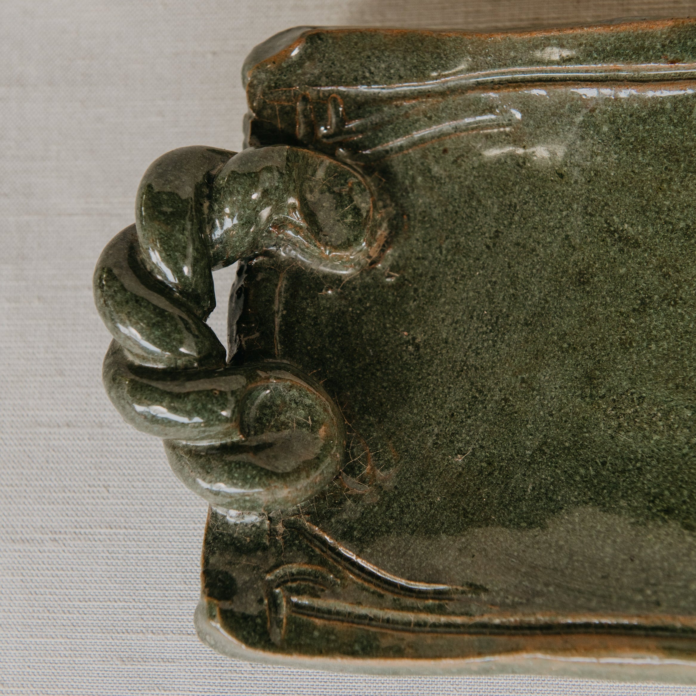 Green ceramic dish with decorative edge on a white background