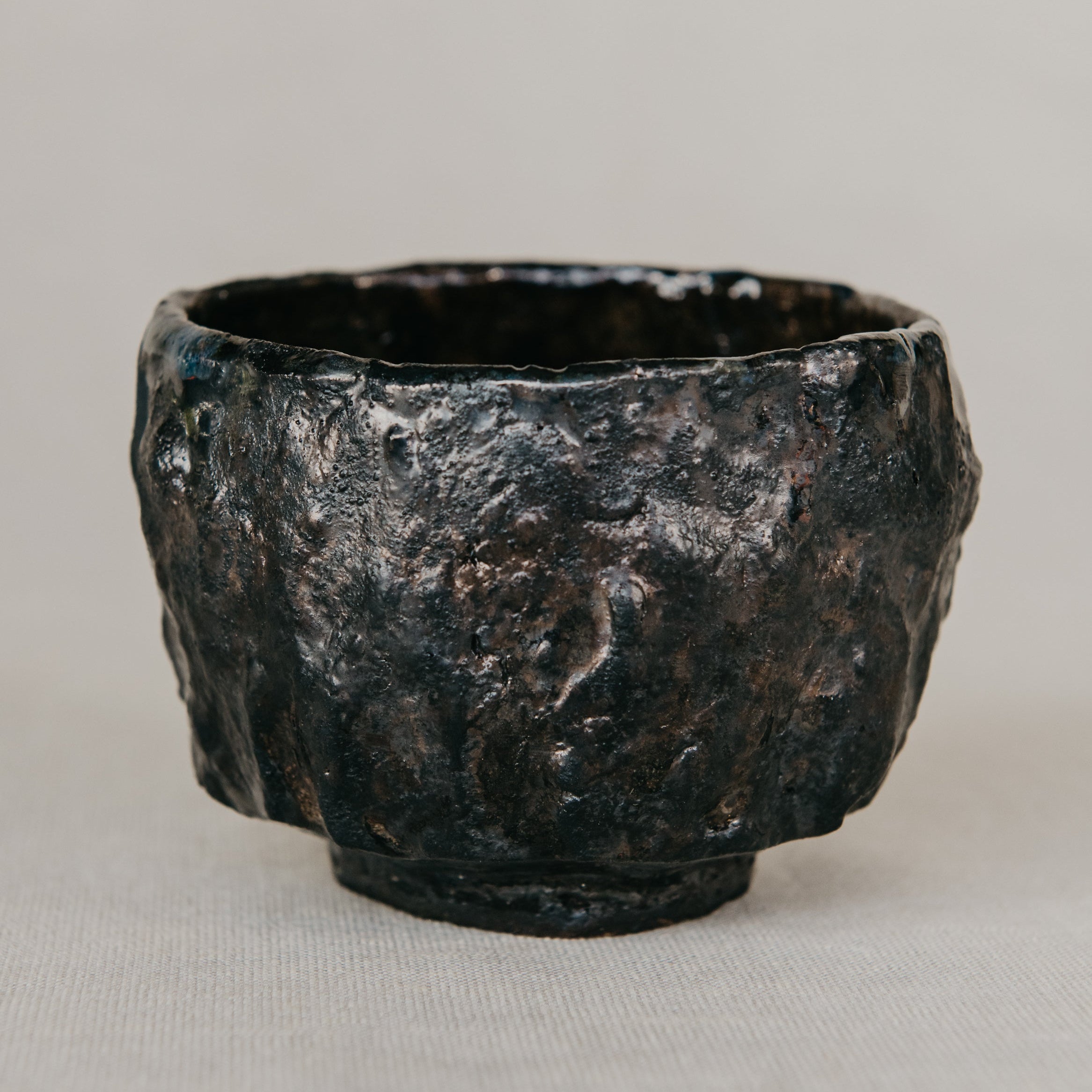 Black ceramic cup with textured surface on a light gray background