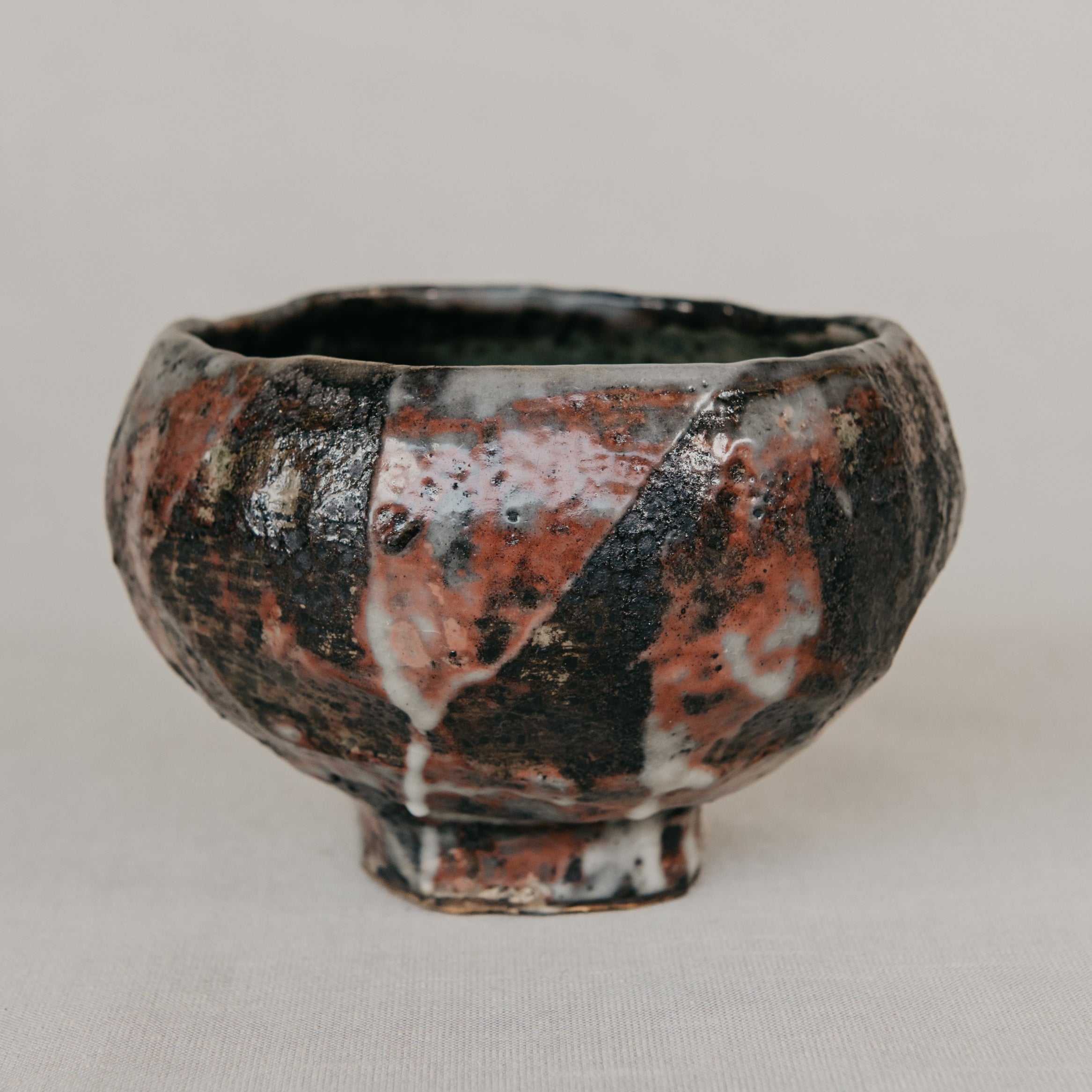 Ceramic bowl with a unique glaze pattern on a plain background