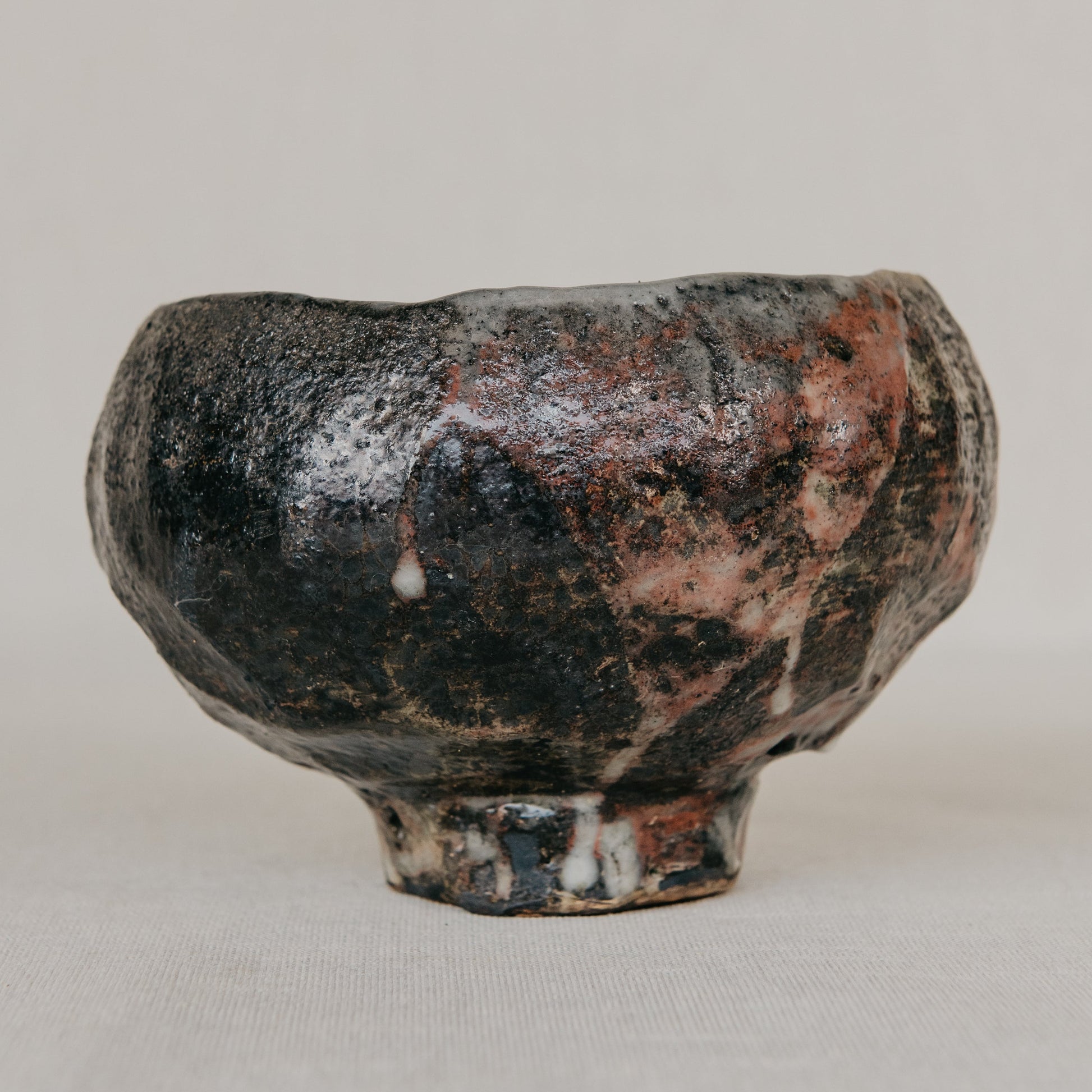 Small ceramic cup with a textured surface on a plain background