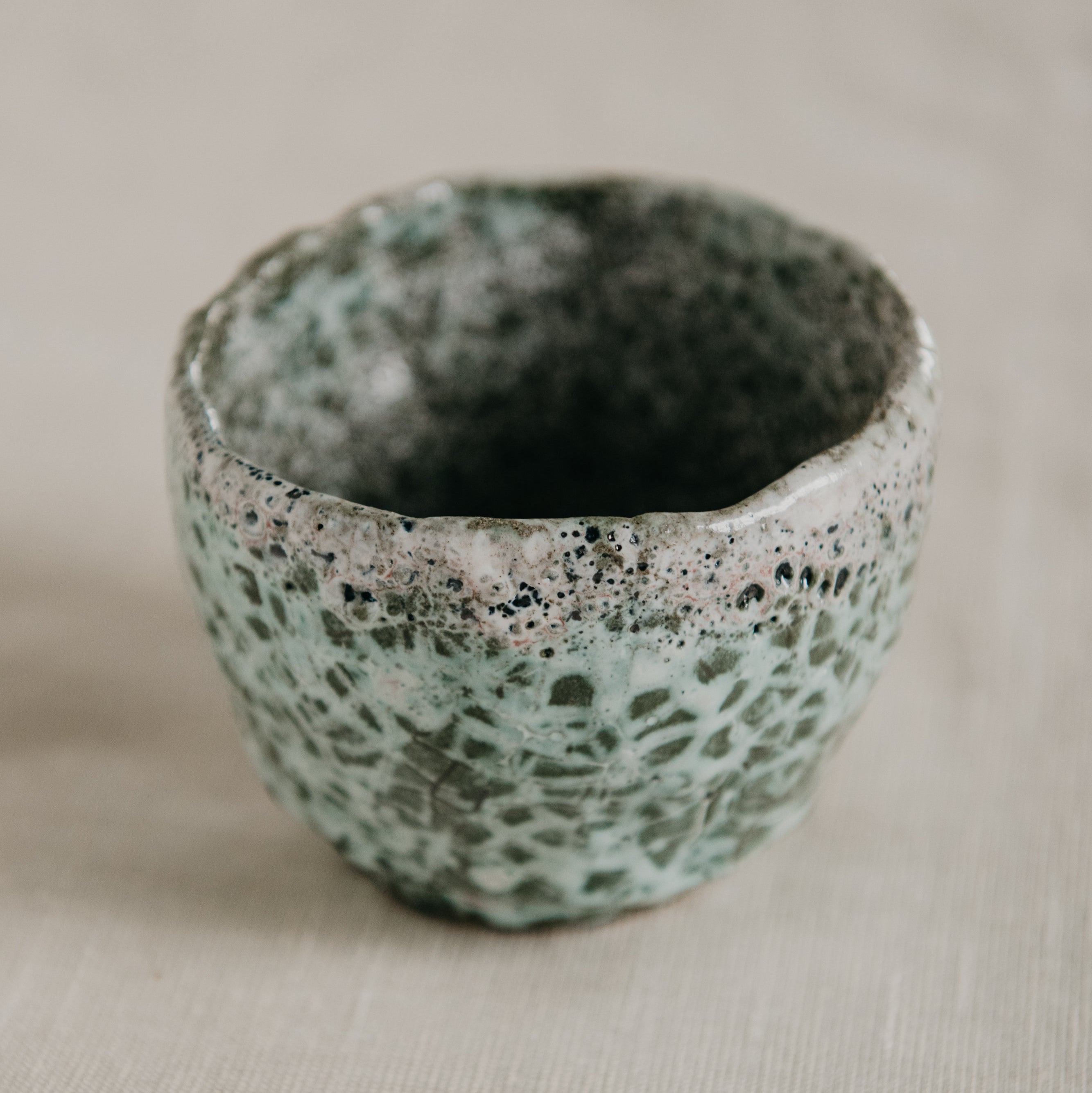Handmade ceramic bowl with textured surface on a beige background