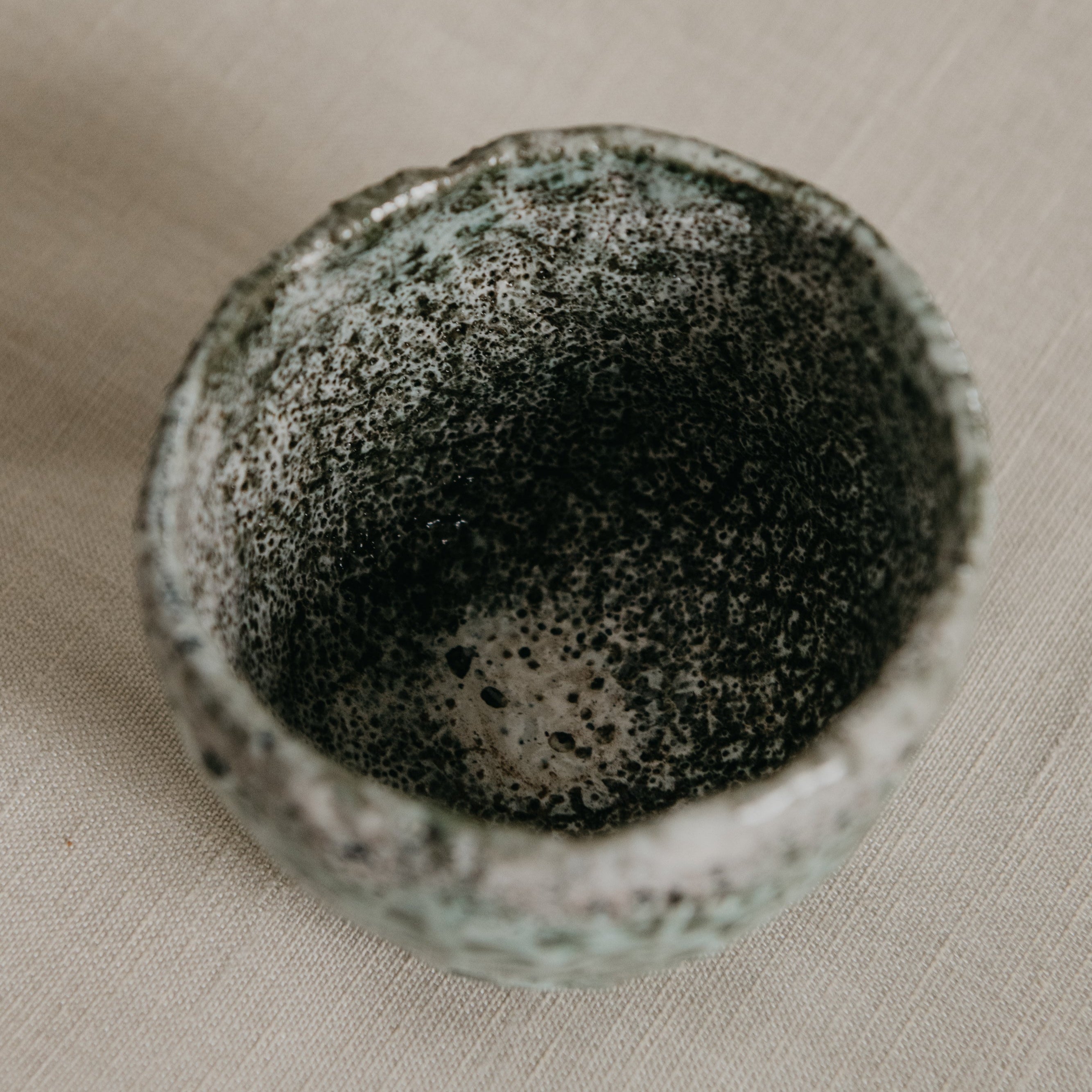 Speckled ceramic bowl on a beige surface