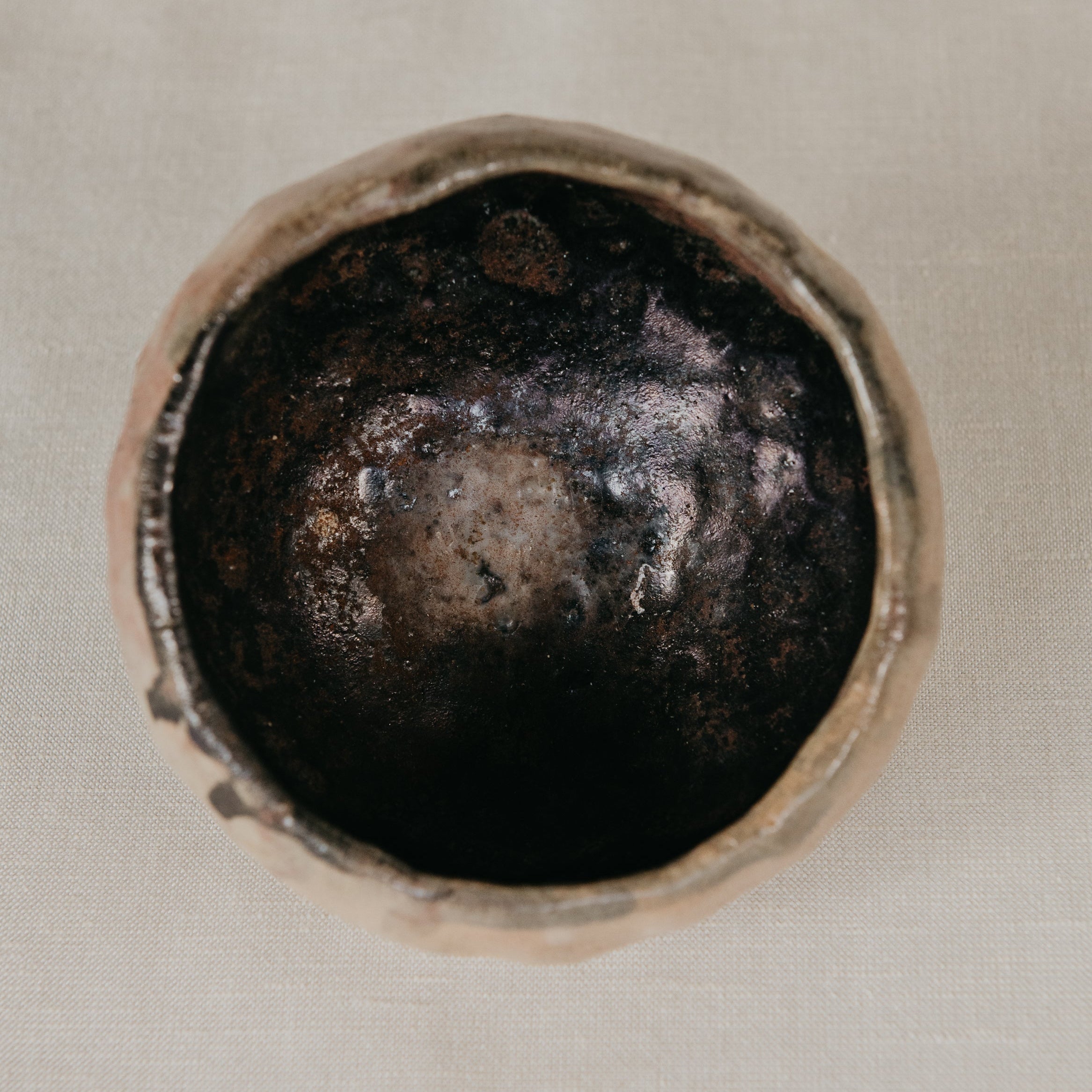 Close-up of a metallic object with a dark center on a beige background