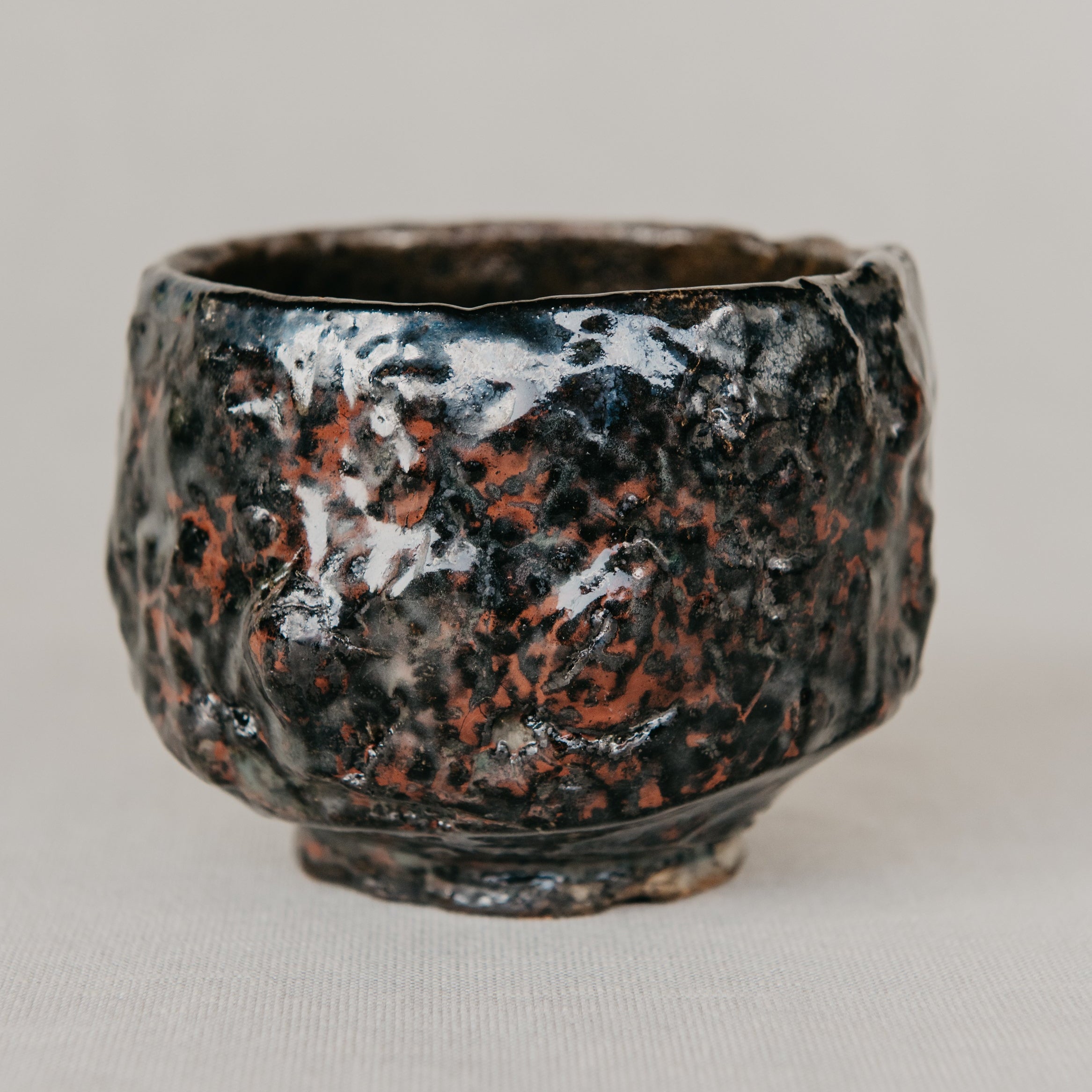 Small ceramic cup with textured surface on a plain background