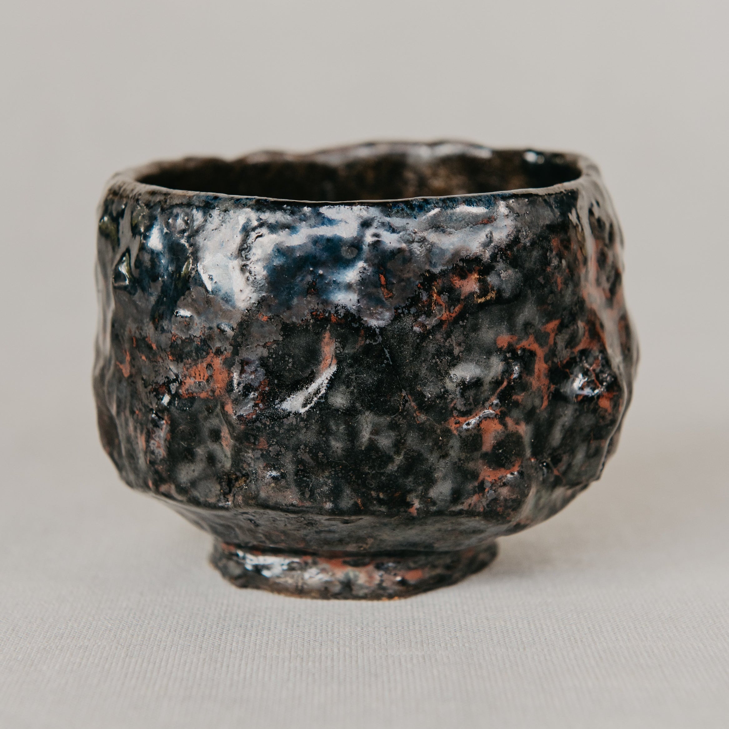 Black ceramic cup with textured surface on a light gray background