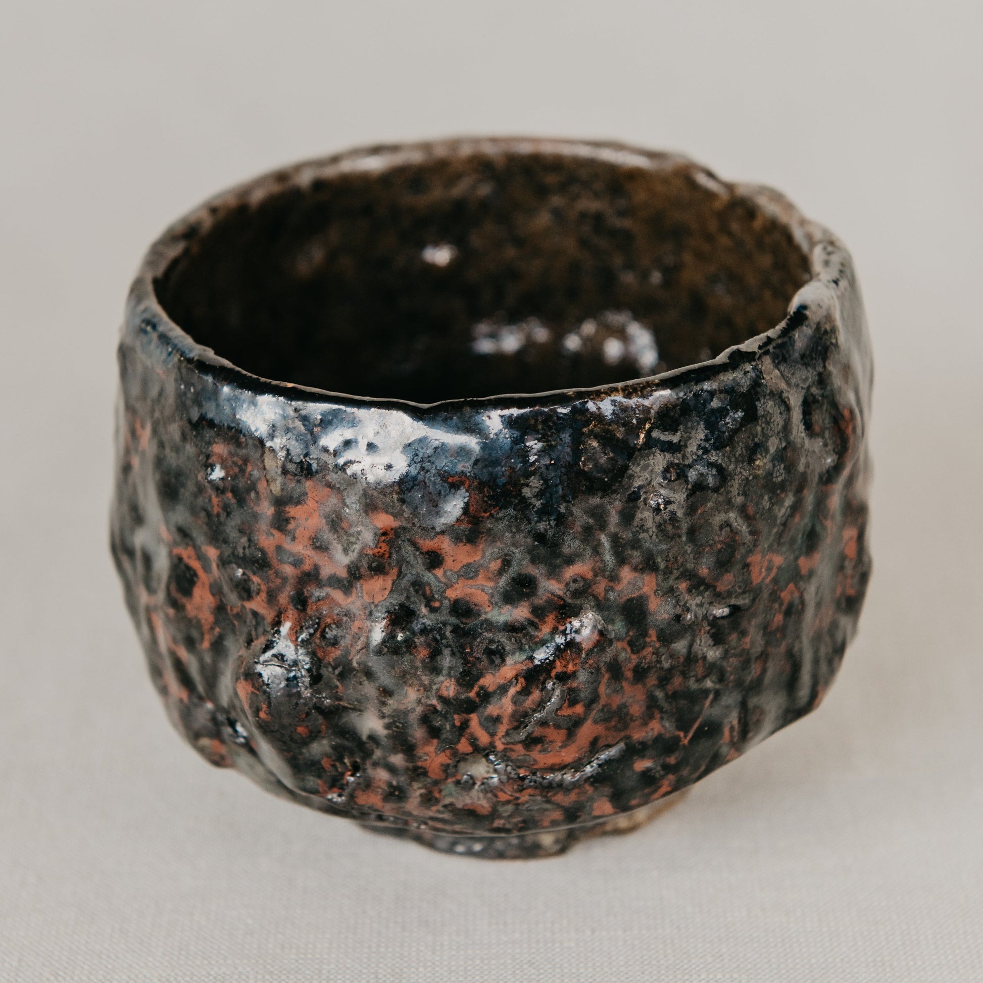 Rustic ceramic cup with textured surface on a neutral background