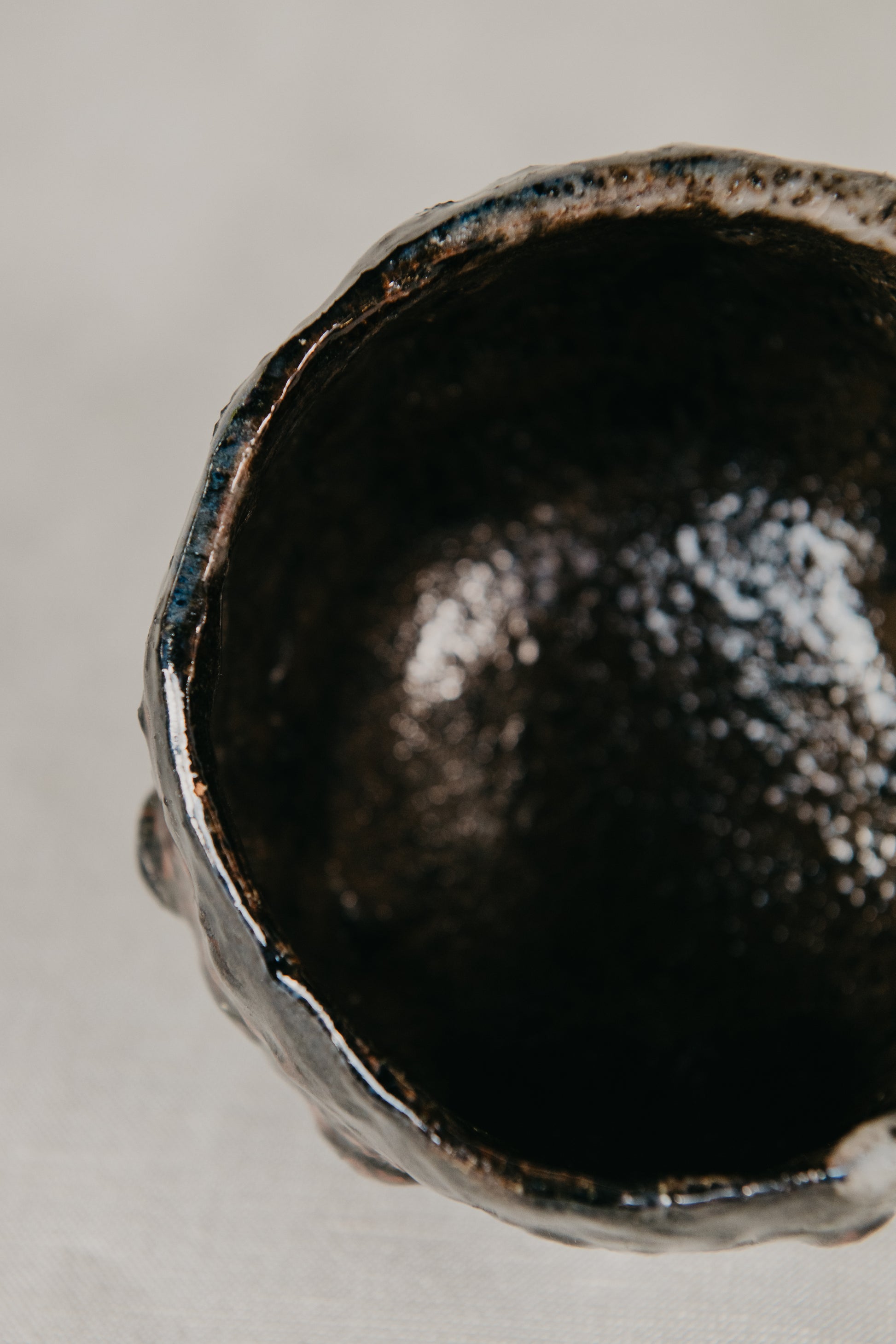Close-up of a textured black ceramic bowl on a neutral background