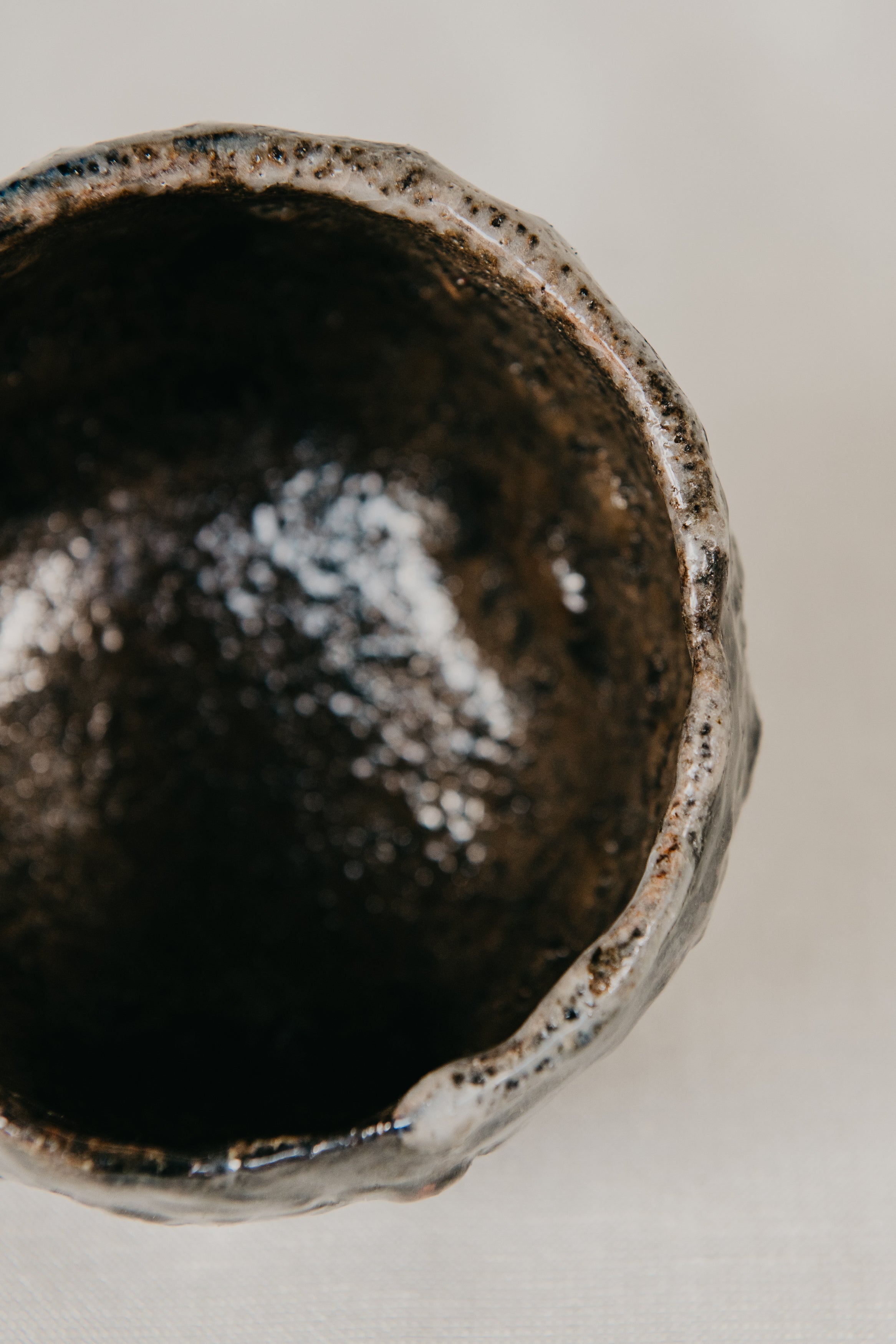Close-up of a dark brown ceramic bowl with a textured surface on a light background