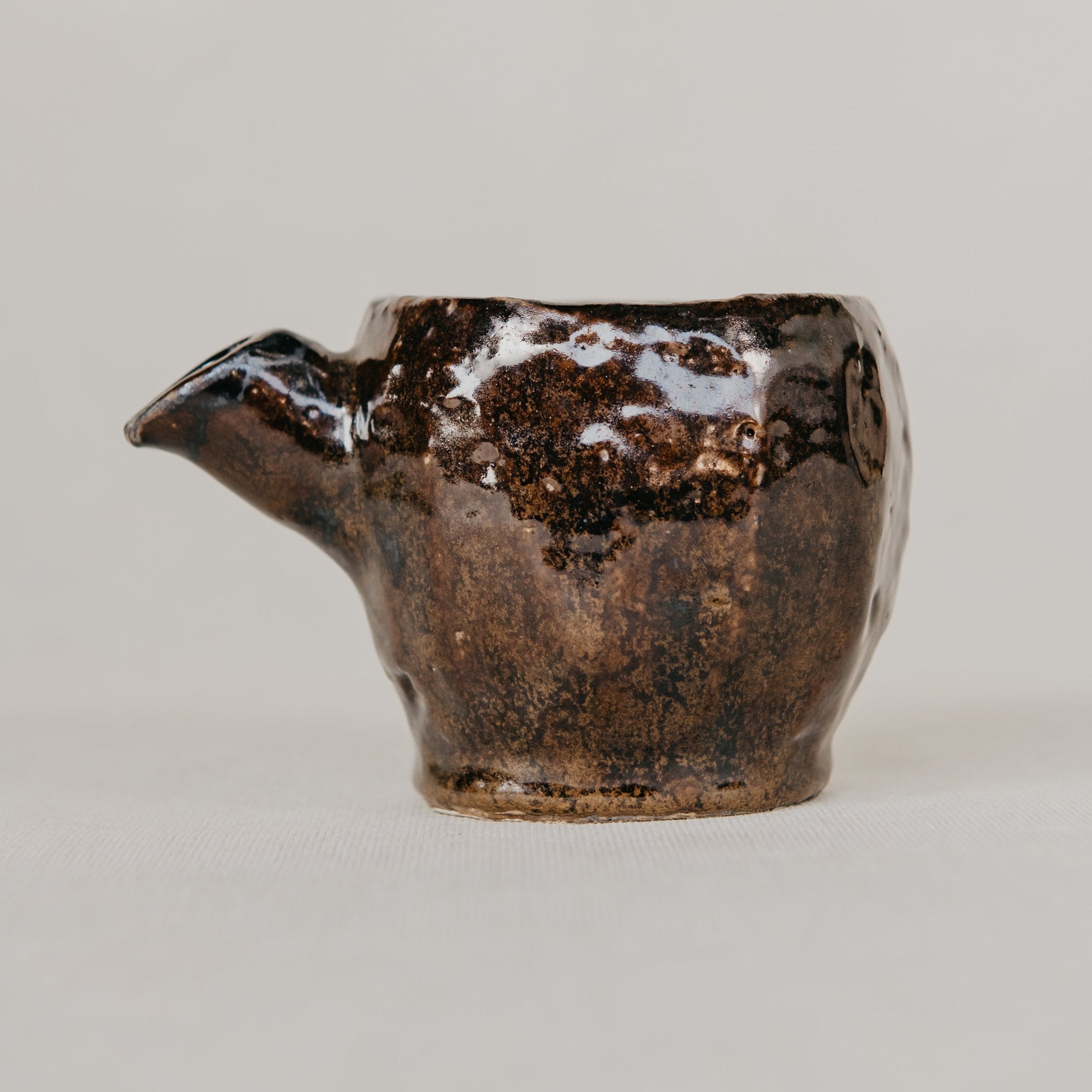 Brown ceramic teapot on a light gray background