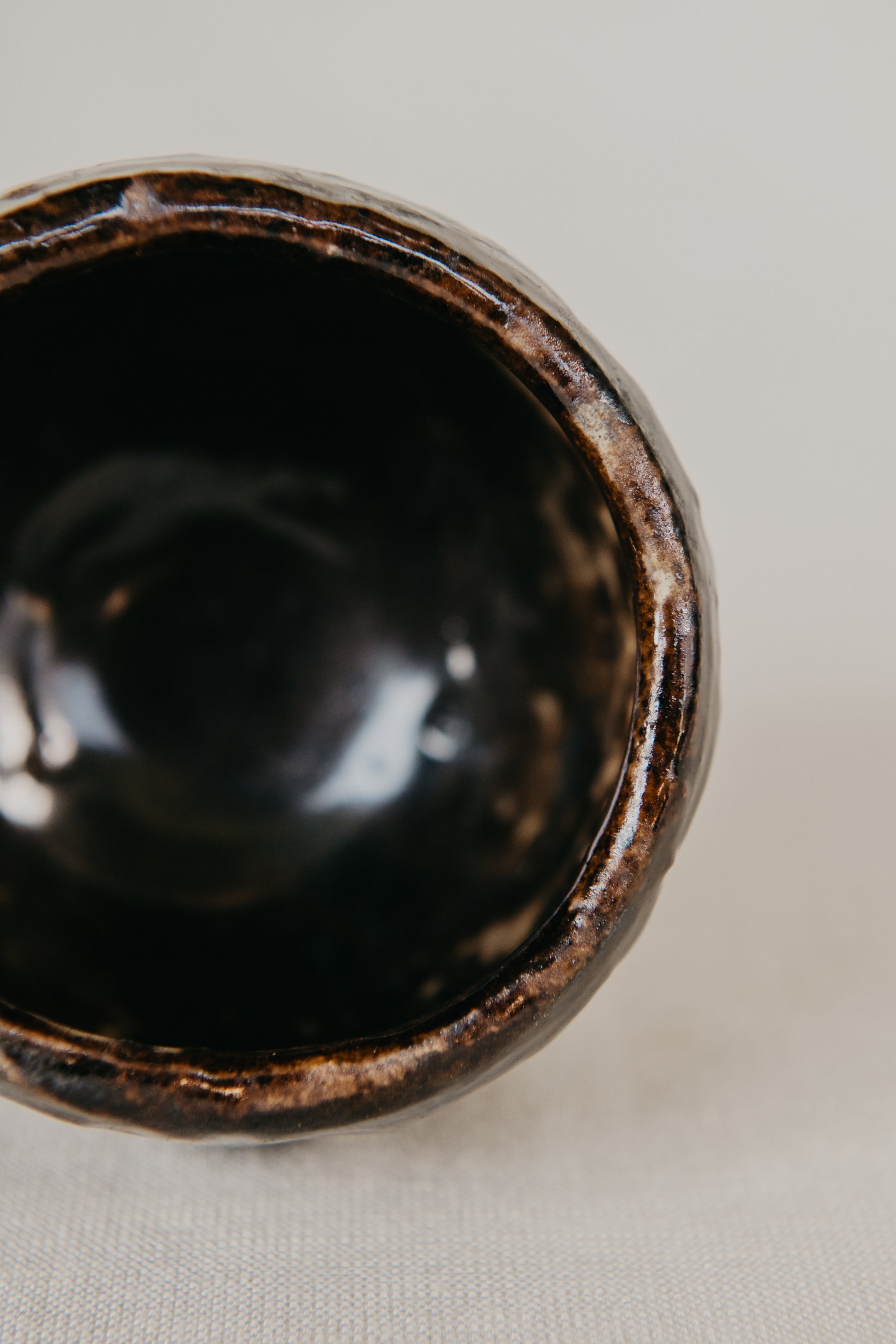 Close-up of a black ceramic bowl with a textured rim on a light background