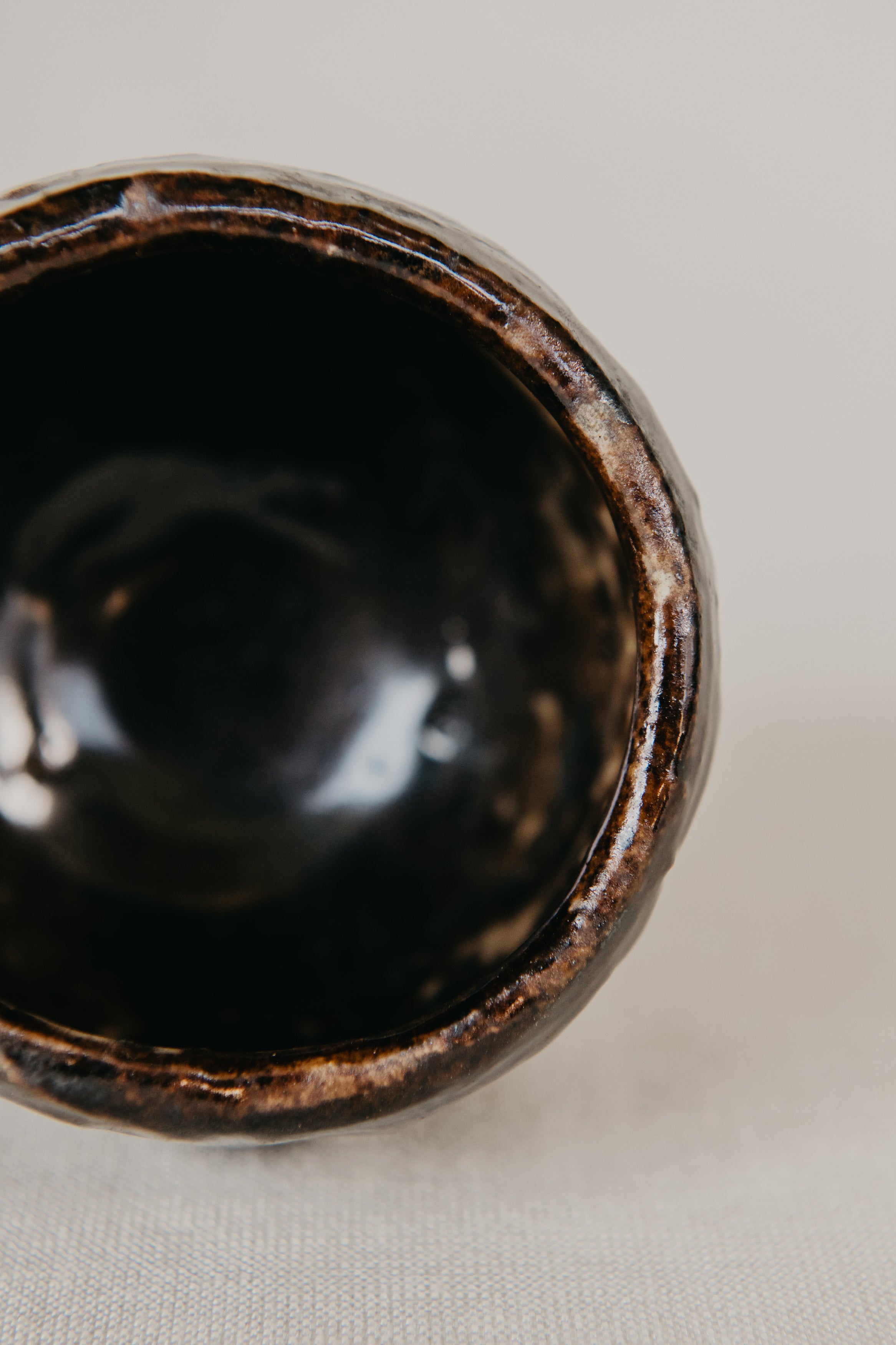 Close-up of a black ceramic bowl with a textured rim on a light background
