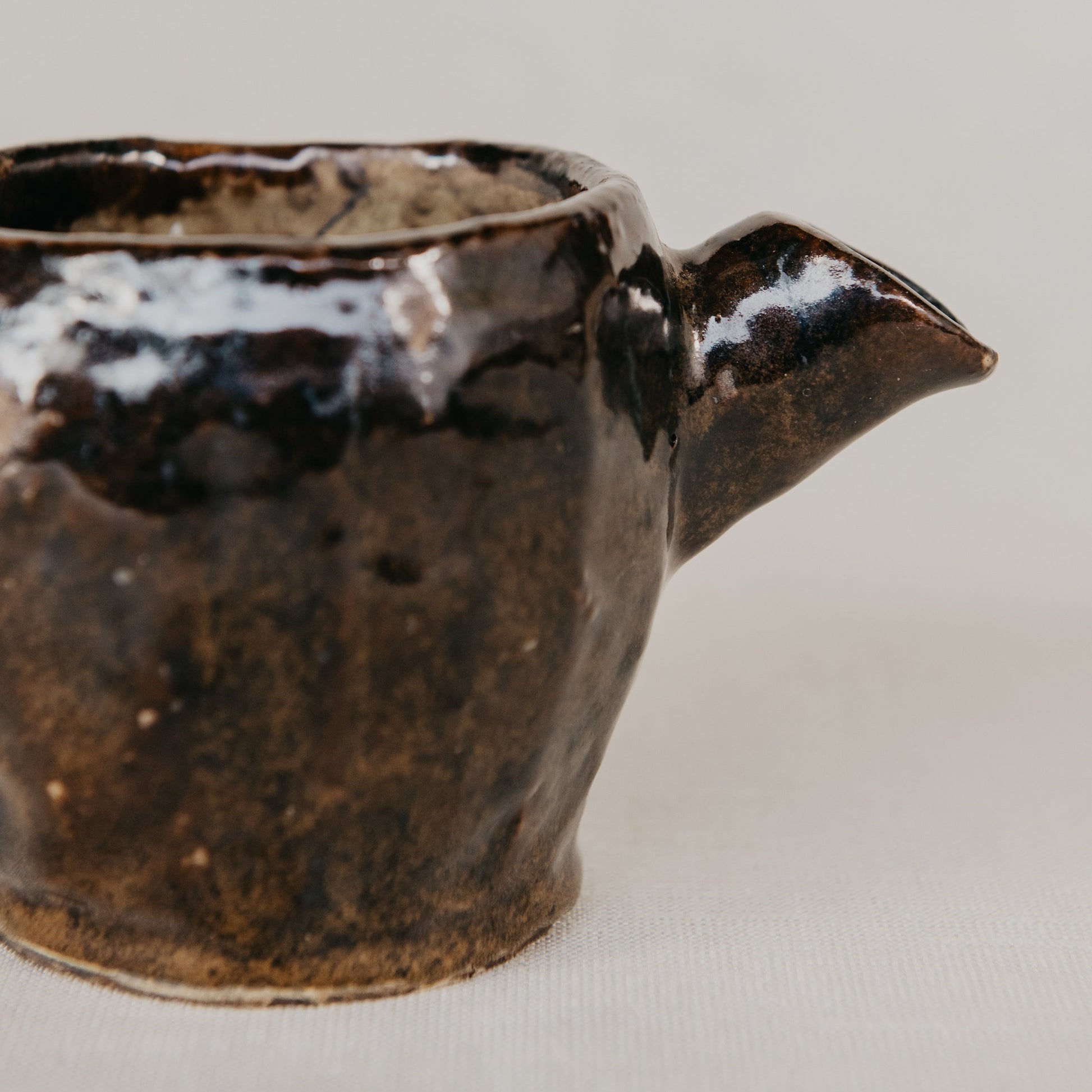 Brown ceramic pitcher on a light gray background