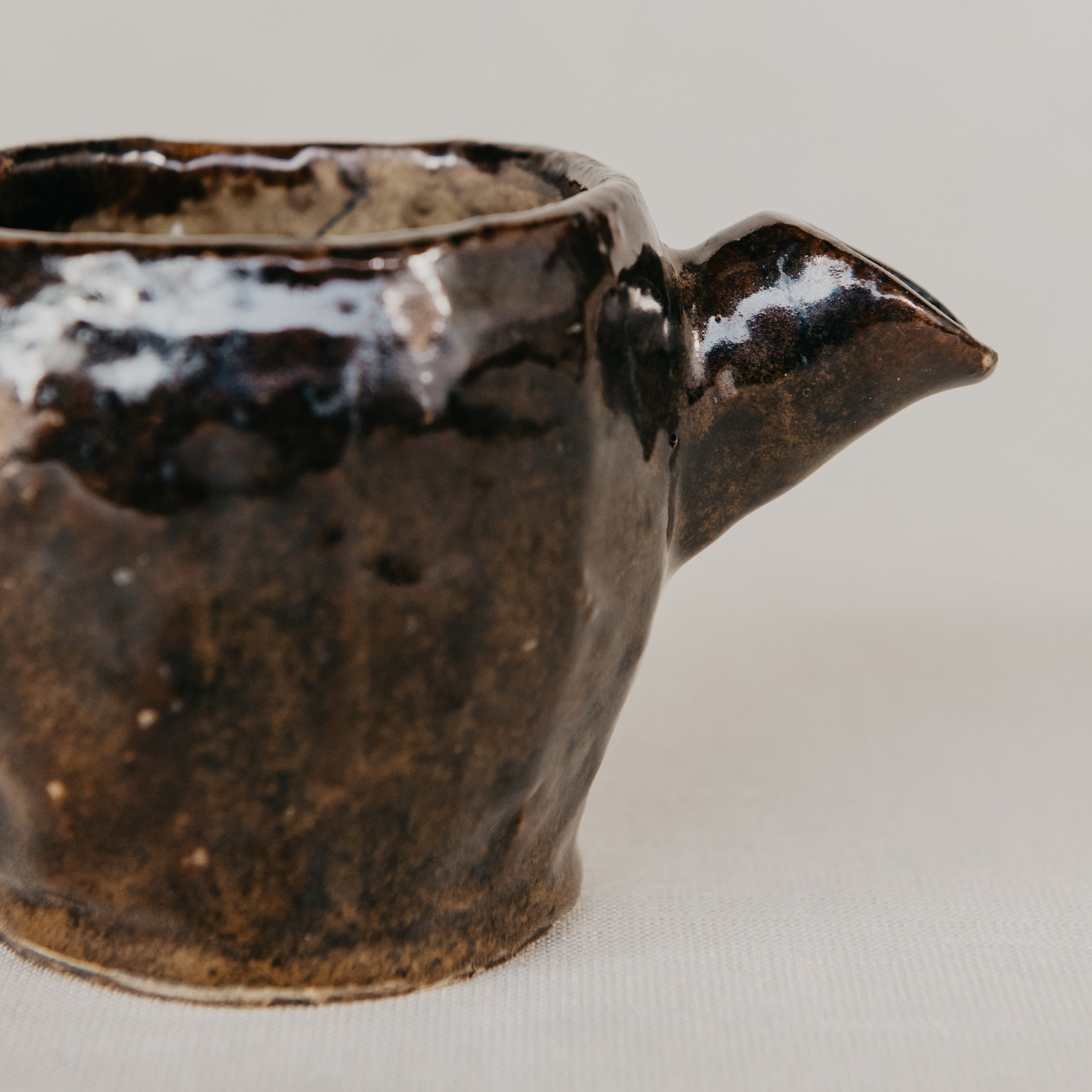 Brown ceramic pitcher on a light gray background