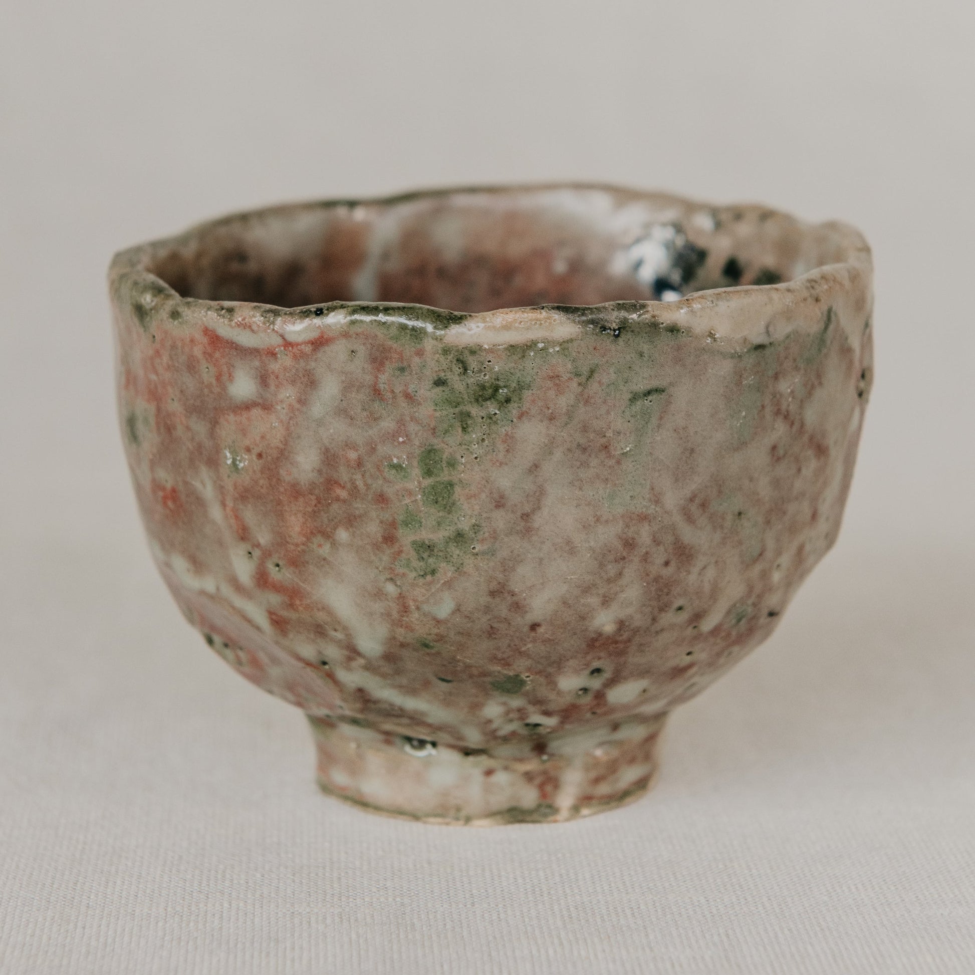 Small ceramic cup with a textured surface on a plain background
