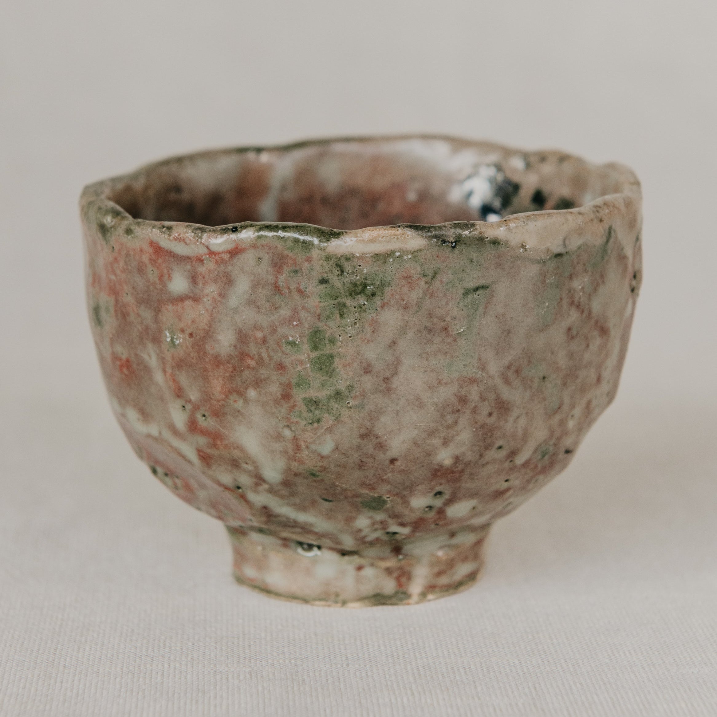 Small ceramic cup with a textured surface on a plain background