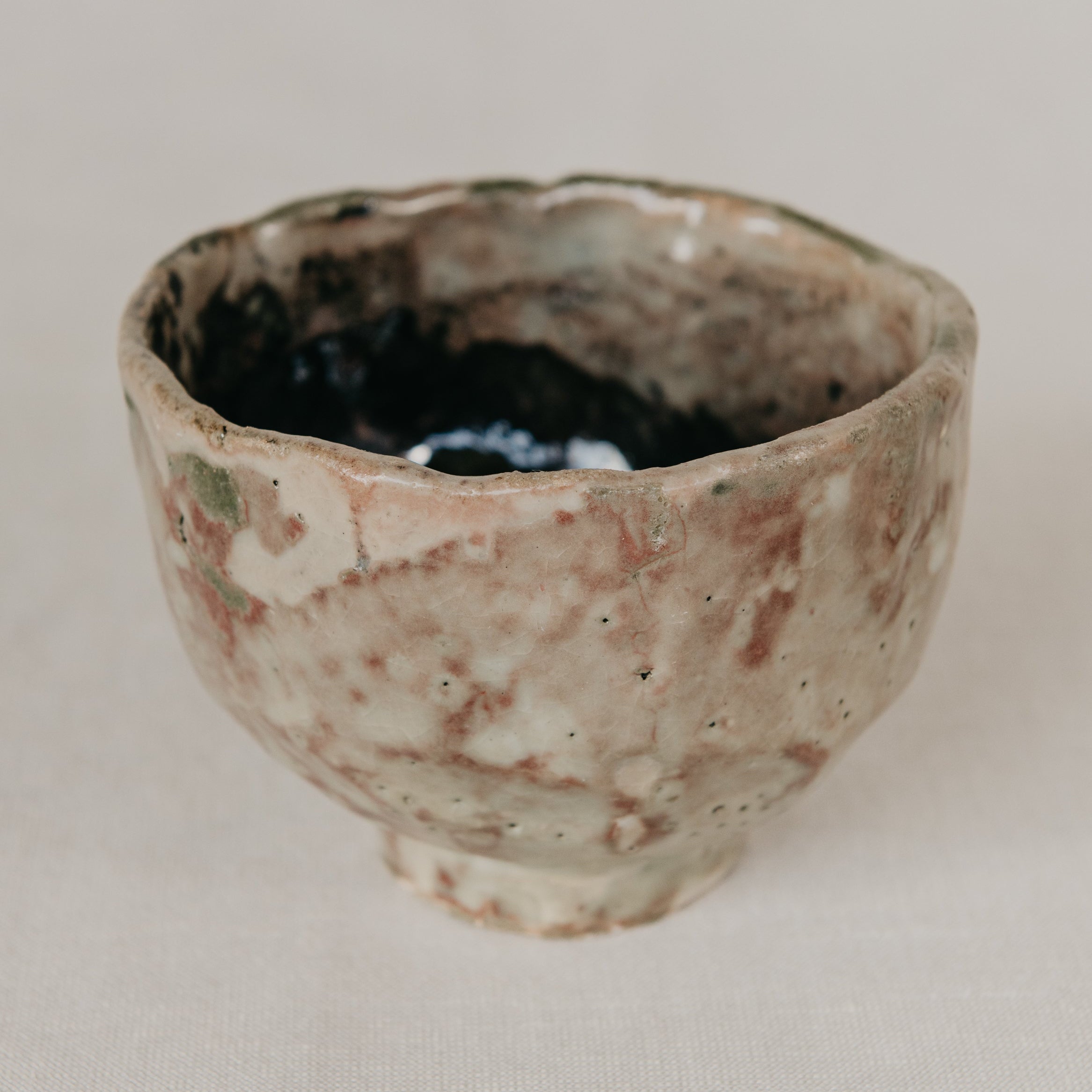 Small ceramic cup with a textured surface on a plain background
